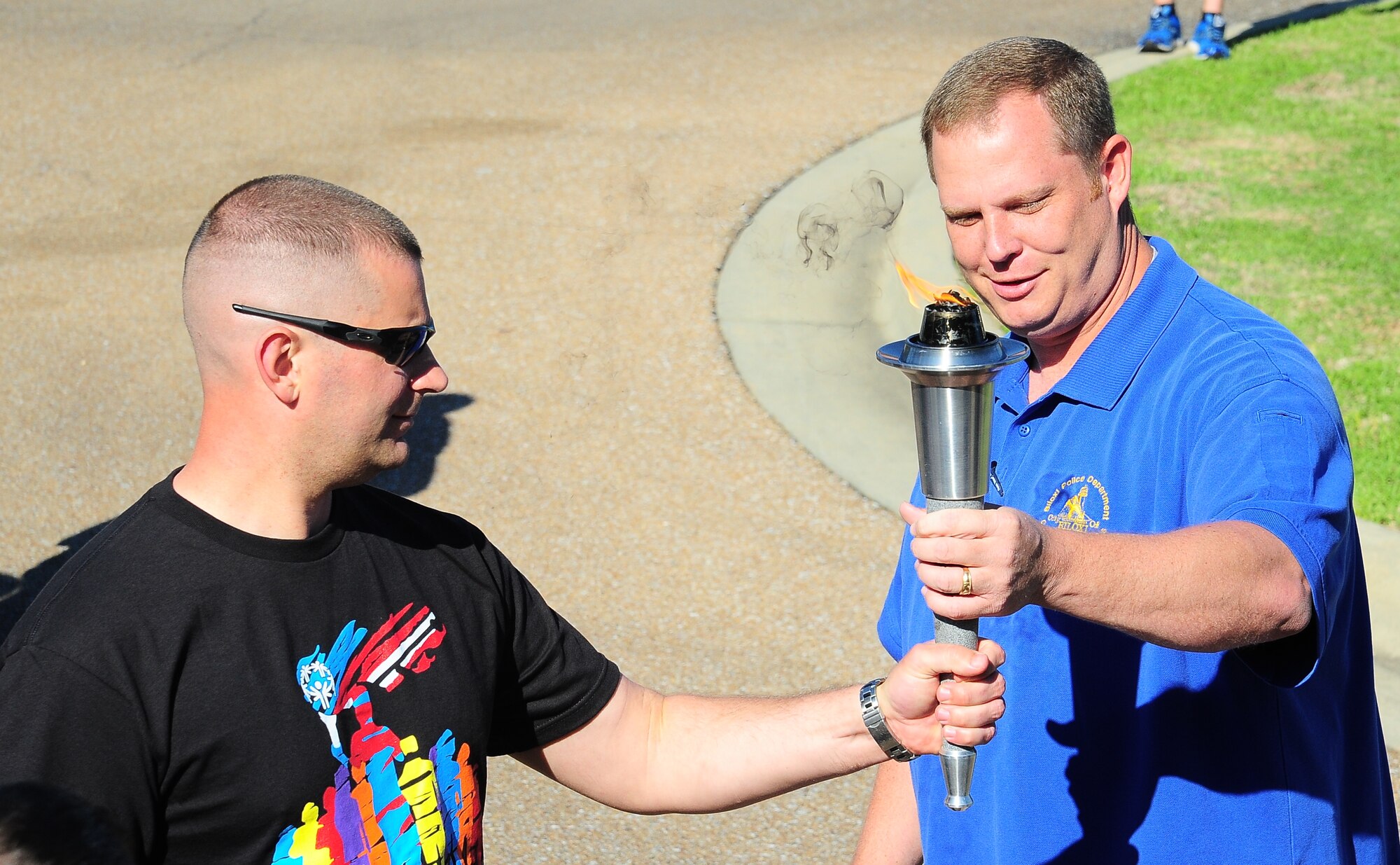 Sgt. Christopher DeBack, Biloxi Police Department, hands the torch over to Maj. Brenton Pickrell, 14th Security Forces Squadron Commander before the beginning of the Torch Run May 6 for Law Enforcement Week. The run was to benefit Mississippi Special Olympics. (U.S. Air Force Photo/Airman 1st Class Daniel Lile)