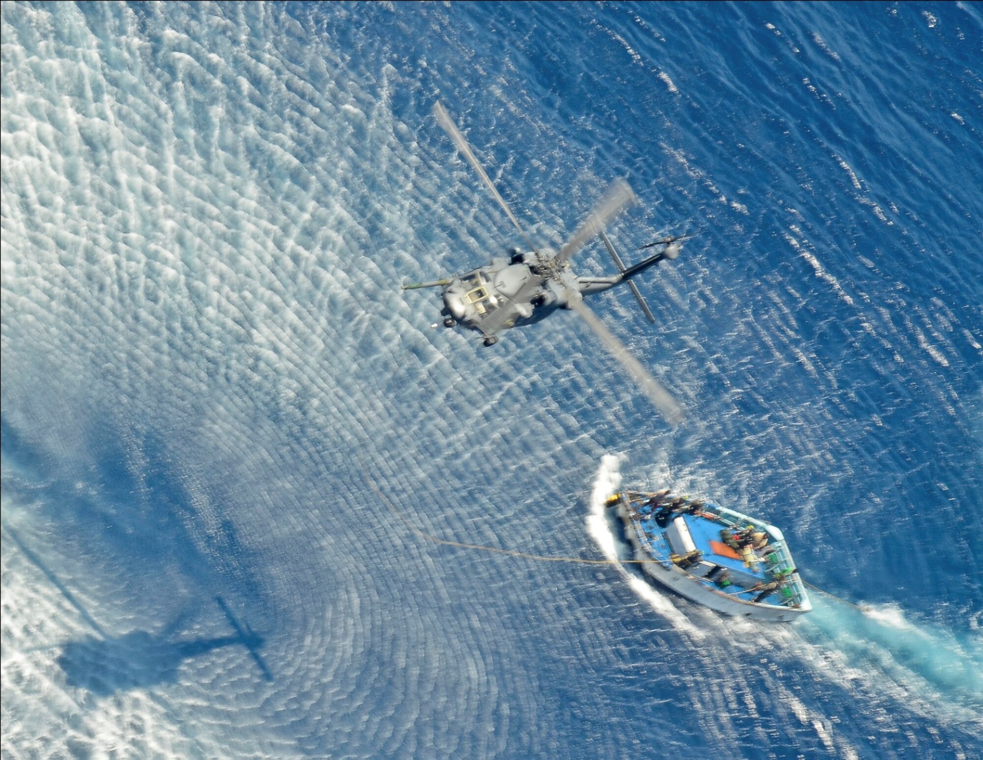 A 55th Rescue Squadron HH-60G Pavehawk helicopter hoists a patient and Pararescueman from a Venezuelan skiff 600 nautical miles off the Pacific Coast of Mexico on May 05, 2014. The Pararescuemen (PJ's) are attached with the patients along the side of the litter, to manage the patient and take care of them medically, and keep them stable.  PJs guided the patient into the helicopter that transported the injured sailors to Cabo San Lucas, Mexico, where they were transferred to a 79th RQS HC-130J Combat King II that will fly them to the University of California, San Diego, Regional Burn Unit. (U.S. Air Force photo by Staff Sgt. Adam Grant/Released)