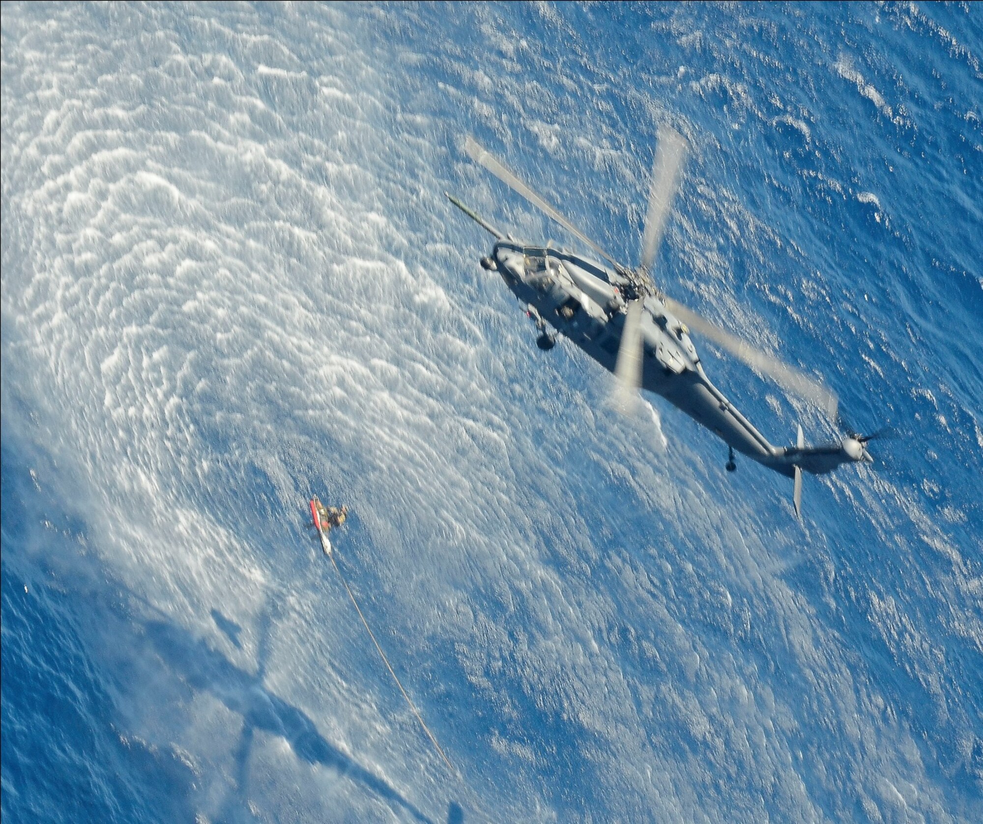 A 55th Rescue Squadron HH-60G Pavehawk helicopter hoists a patient and Pararescueman from a Venezuelan skiff 600 nautical miles off the Pacific Coast of Mexico on May 05, 2014. The Pararescuemen (PJ's) are attached with the patients along the side of the litter, to manage the patient and take care of them medically, and keep them stable.  PJs guided the patient into the helicopter that transported the injured sailors to Cabo San Lucas, Mexico, where they were transferred to a 79th RQS HC-130J Combat King II that will fly them to the University of California, San Diego, Regional Burn Unit. (U.S. Air Force photo by Staff Sgt. Adam Grant/Released)