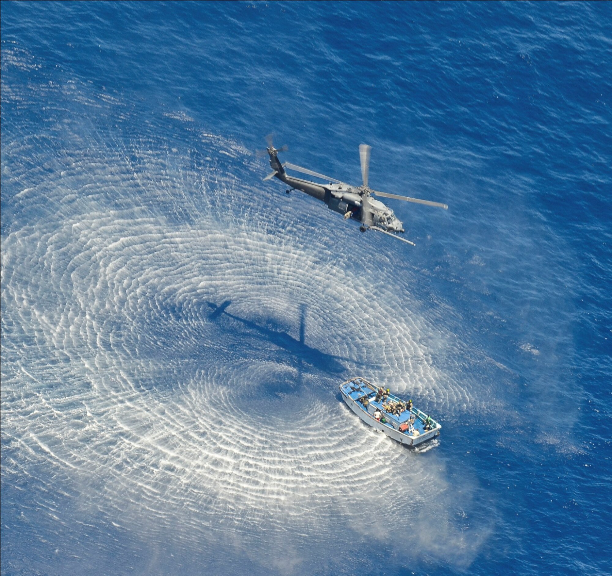 A 55th Rescue Squadron (RQS) HH-60G Pavehawk helicopter hovers above a skiff to hoist critically burned sailors 600 nautical miles off the Pacific Coast of Mexico on May 05, 2014. The Pararescuemen (PJ's) are attached with the patients along the side of the litter, to manage the patient and take care of them medically, and keep them stable.  PJs guided the patient into the helicopter that transported the injured sailors to Cabo San Lucas, Mexico, where they were transferred to a 79th RQS HC-130J Combat King II that will fly them to the University of California, San Diego, Regional Burn Unit. (U.S. Air Force photo by Staff Sgt. Adam Grant/Released)