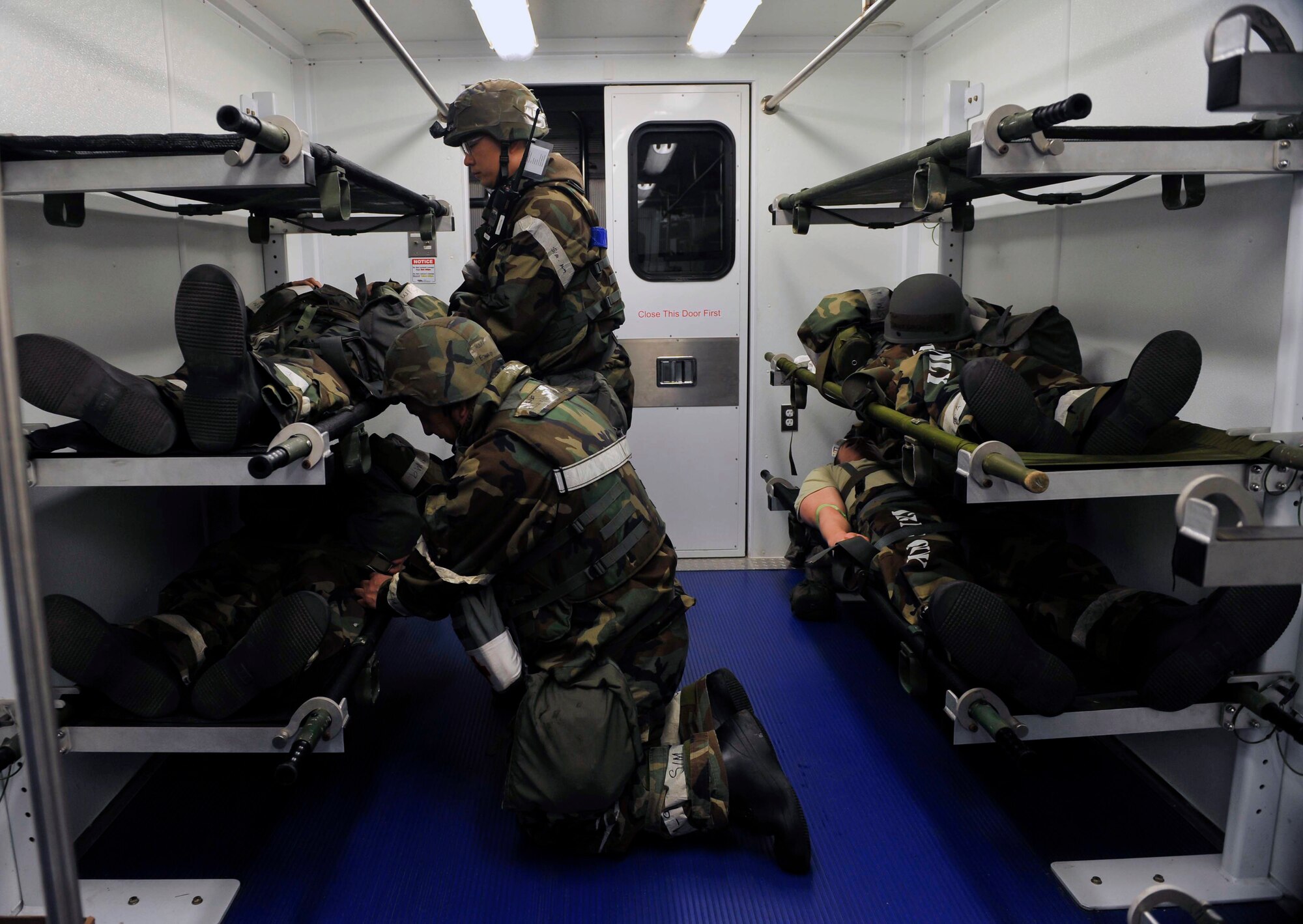 Airmen from the 51st Medical Group tighten the straps on the NATO litter prior to moving the high-deck patient loading platform vehicle May 8 near the emergency room during a simulated patient transfer Osan Air Base, Republic of Korea. The HDPLP vehicle has a series of hoists that allow the cab and patient seating area of the vehicle to rise to the level of the entrance of an aircraft. (U.S. Air Force photo by Senior Airman David Owsianka)