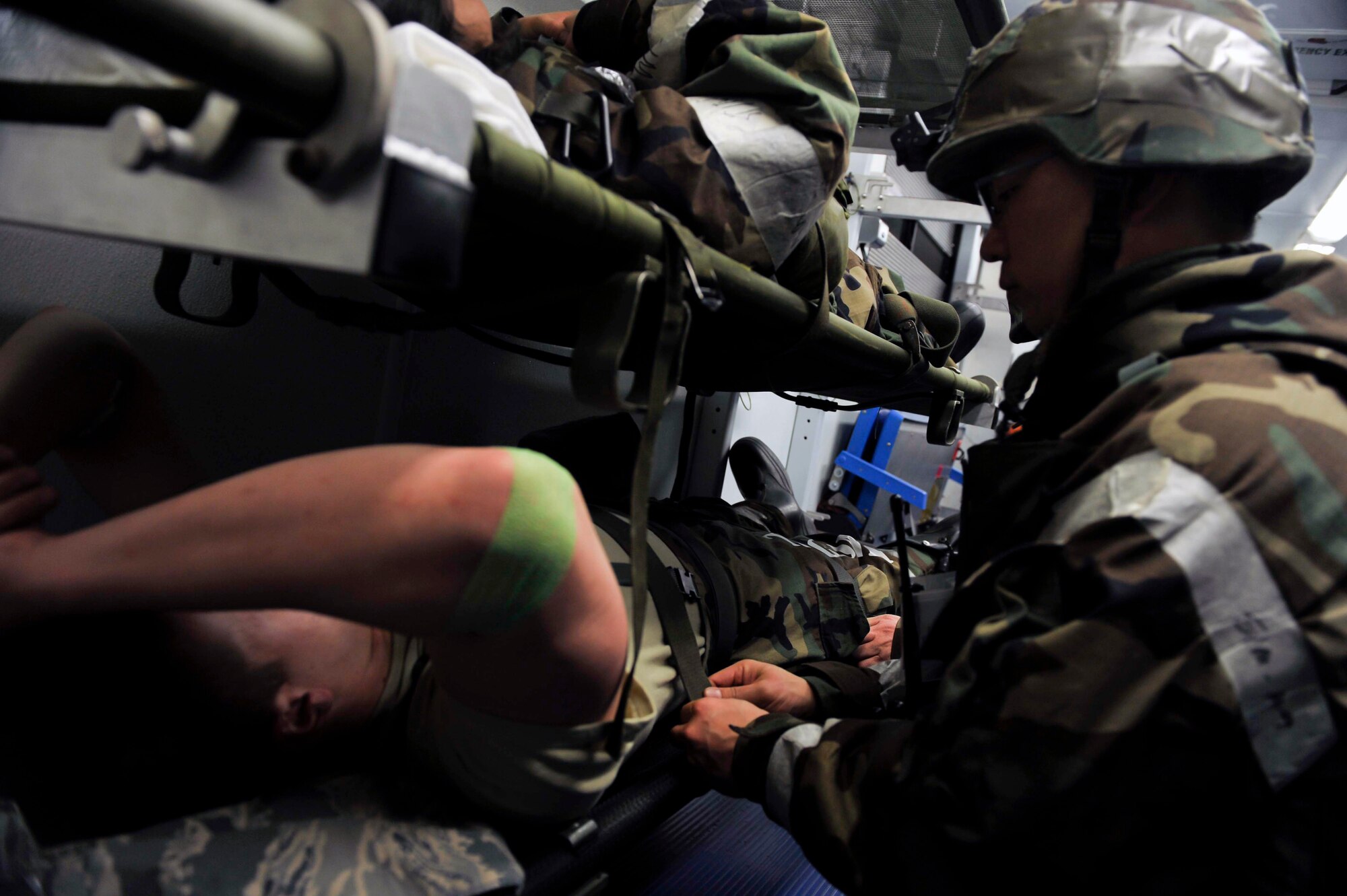 An Airman from the 51st Medical Group tightens a harness on Airman 1st Class Kyle Maldonado, 51st Security Forces Squadron, prior to moving the high-deck patient loading platform vehicle May 8 near the emergency room during a simulated patient transfer Osan Air Base, Republic of Korea. The HDPLP vehicle has a series of hoists that allow the cab and patient seating area of the vehicle to rise to the level of the entrance of an aircraft. (U.S. Air Force photo by Senior Airman David Owsianka)