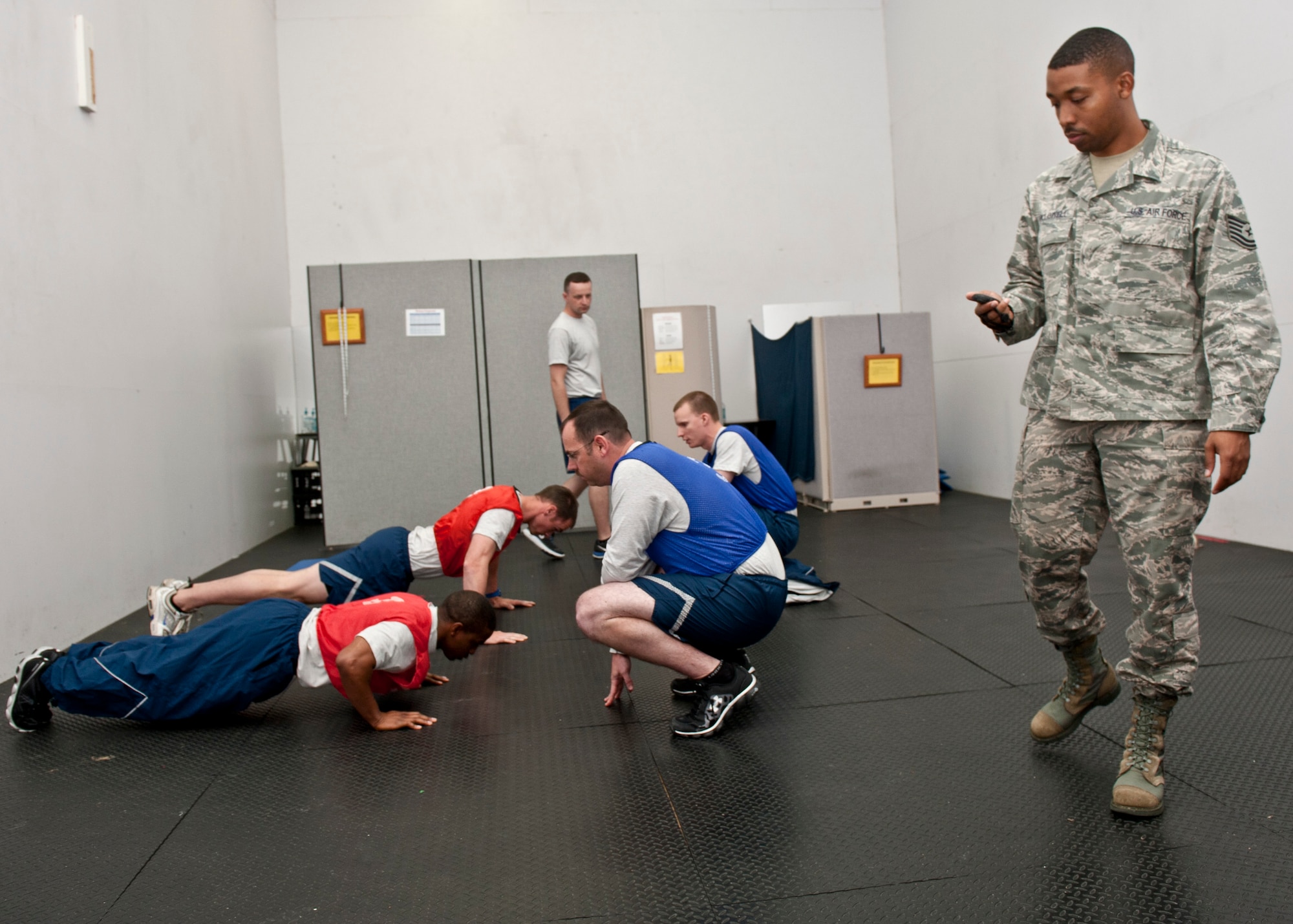 U.S. Air Force Tech. Sgt. Billy Hollowell, 633rd Force Support Squadron Fitness Assessment Cell manager, times U.S. Air Force Airmen as they perform pushups during a fitness assessment test at Langley Air Force Base, Va., May 6, 2014. The fitness center staff’s goal is to motivate Airmen to participate in a physical conditioning program that emphasizes total fitness, to include proper aerobic conditioning, strength and flexibility training as well as healthy eating. Hollowell is from Detroit, Mich. (U.S. Air Force photo by Senior Airman Connor Estes/Released)