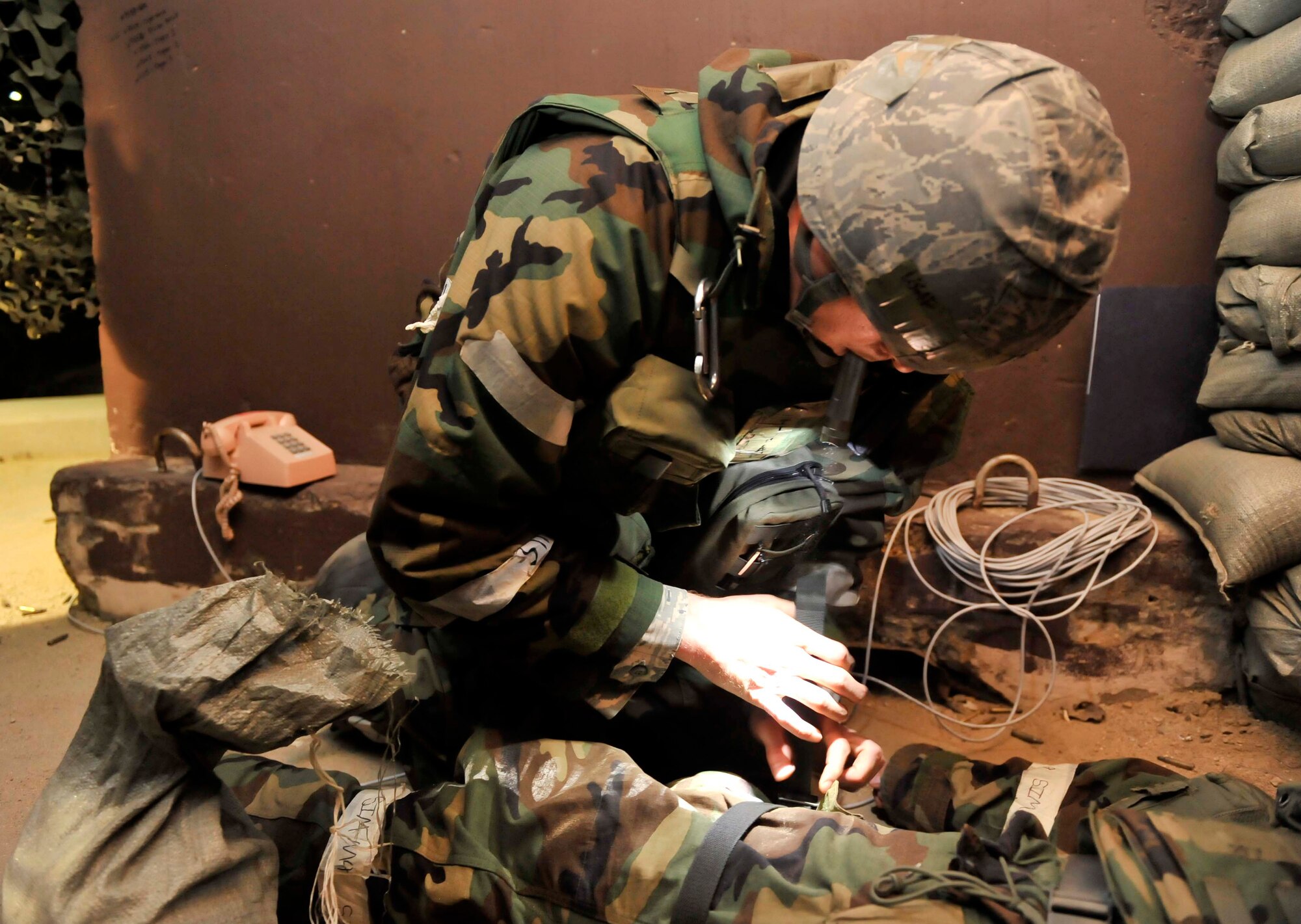Staff Sgt. Travis Lewis, 51st Communication Squadron, applies a tourniquet onto the leg of Airman 1st Class Eryk Bilicki, 51st CS, after getting shot by opposition forces May 7 during a simulated attack on Osan Air Base, Republic of Korea. The scenario was held to help the Airmen improve their response capabilities if they were attacked in a real world scenario. (U.S. Air Force photo by Senior Airman David Owsianka)