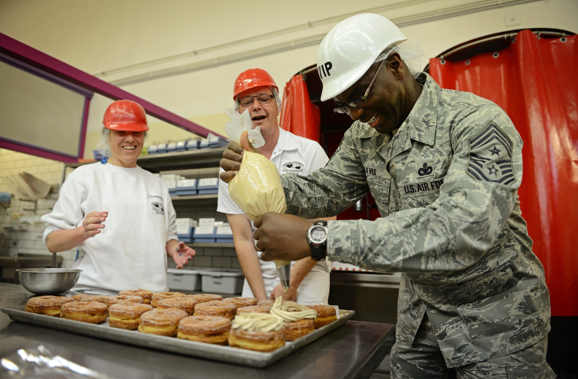 Chief Master Sgt. James E. Davis, U.S. Air Forces Europe and Air Forces Africa command chief, tries his hand at decorating donuts during a familiarization tour in Gruenstadt, Germany, April 30, 2014. The Gruenstadt facility is the central production location for more than 250 line items, as well as cold storage for 200 line items and even produces five million gallons of Culligan bottled water each year. The plant distributes to more than 100 locations in 25 countries and has been in business since 1953. (U.S. Air Force photo/ Staff Sgt. Ryan Crane)