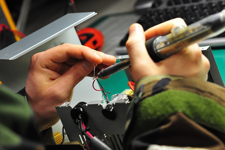 U.S. Air Force Airman 1st Class Andrew Woods, 35th Communications Squadron client systems technician, solders wires on the power supply of a base system at Misawa Air Base, Japan, May 7, 2014. When any of the base's mobile communication equipment breaks down, Woods and his team troubleshoot and fix the problem. (U.S. Air Force photo/Senior Airman Jose Hernandez-Domitilo)