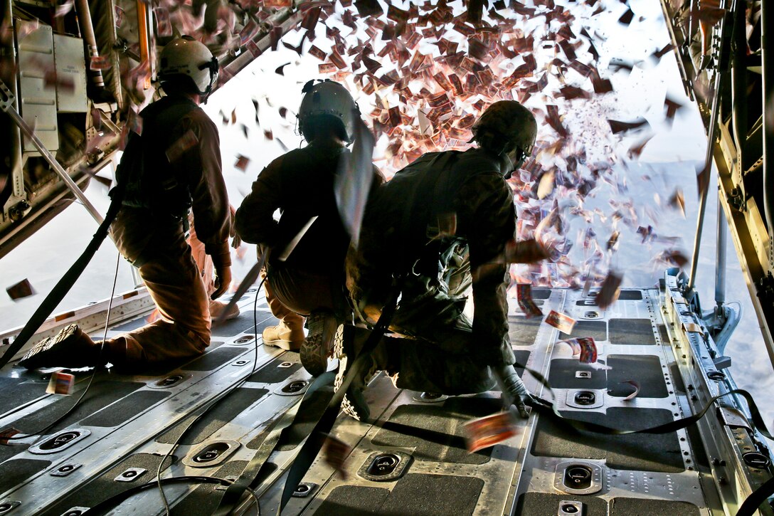 U.S. Marine Corps Cpl. Jameson Dudley, left, and U.S. Army Sgt. Nijoku Odom, right, throw leaflets from a KC-130 Super Hercules aircraft over southern Afghanistan, Aug. 28, 2013. Dudley, a crew master, is assigned to Marine Aerial Refueler Transport Squadron 252, and Odom, an intelligence analyst, is assigned to the 303rd Psychological Operations Company. Crews dropped leaflets to support operations to defeat insurgency influence in the area.  
