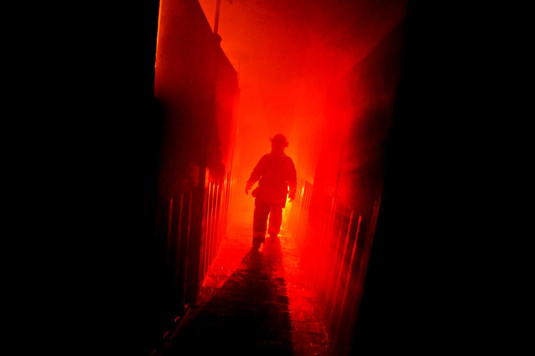 A airman walks down a hallway towards the flames during training at the Suffolk County Fire Academy in Yaphank, N.Y., Aug. 6, 2013. The airman is a firefighter assigned to the New York Air National Guard's 106th Rescue Wing on Gabreski Air National Guard Base in Westhampton Beach, NY. The firefighters reviewed basic skills in a realistic training environment under the eye of civilian firefighter trainers.  
