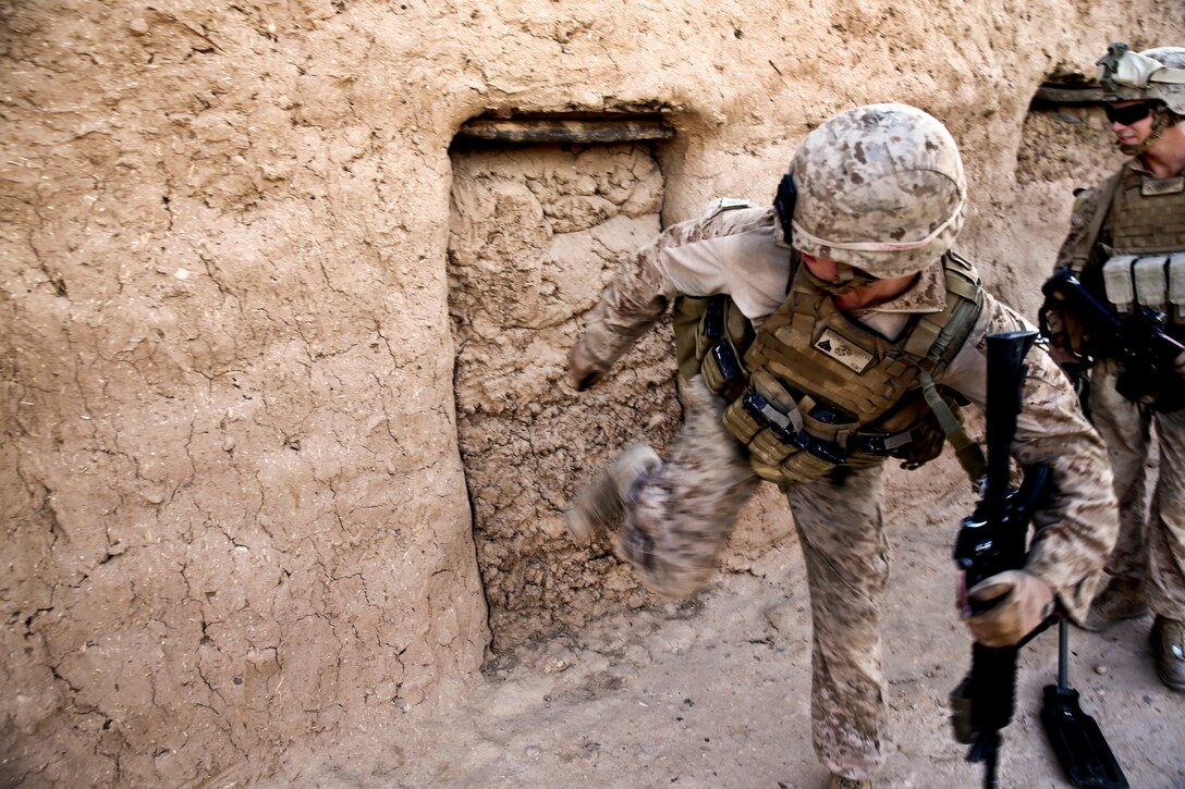 U.S. Marine Corps Cpl. Jarrett Goff kicks a wall in an empty compound during a patrol in Washir village in Helmand province, Afghanistan, July 29, 2013. Goff, a team leader, is assigned to Fox Company, 2nd Battalion, 2nd Marine Regiment.  

