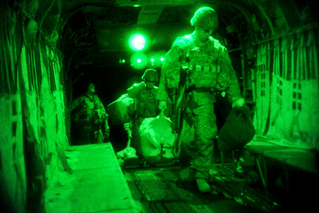 As seen through a night-vision device, U.S. soldiers carry their equipment onboard a CH-47 Chinook helicopter before night missions on Forward Operating Base Fenty in Nangarhar province, Afghanistan, July 22, 2013.  
