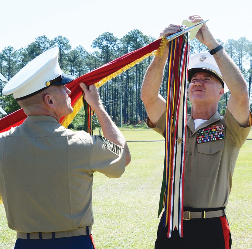 Maj. Gen. Charles L. Hudson, commanding general, Marine Corps Installations Pacific and commander, Marine Corps Base Camp Butler, Okinawa, Japan (right), affixes the Meritorious Unit Commendation streamer to Marine Corps Logistics Command’s colors while Sgt. Maj. Joseph M. Davenport, sergeant major, LOGCOM, assists.  Hudson, LOGCOM’s former commanding general, was invited to participate in the ceremony held in front of LOGCOM’s headquarters, Tuesday. 