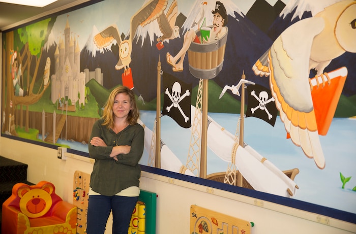 Gwyn Korpi, a military spouse and graphic designer, stands near a mural she painted at the at the children’s area of the Harriotte B. Smith Library aboard Marine Corps Base Camp Lejeune. The mural is designed to pique children’s interests with a fairy tale world that could be the setting of many works of children’s fiction. 