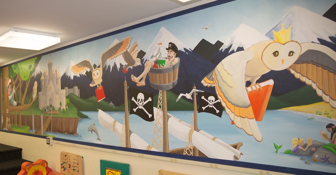 Gwyn Korpi, a military spouse and graphic designer, painted a mural at the at the children’s area of the Harriotte B. Smith Library aboard Marine Corps Base Camp Lejeune. The mural is designed to pique children’s interests with a fairy tale world that could be the setting of many works of children’s fiction. 