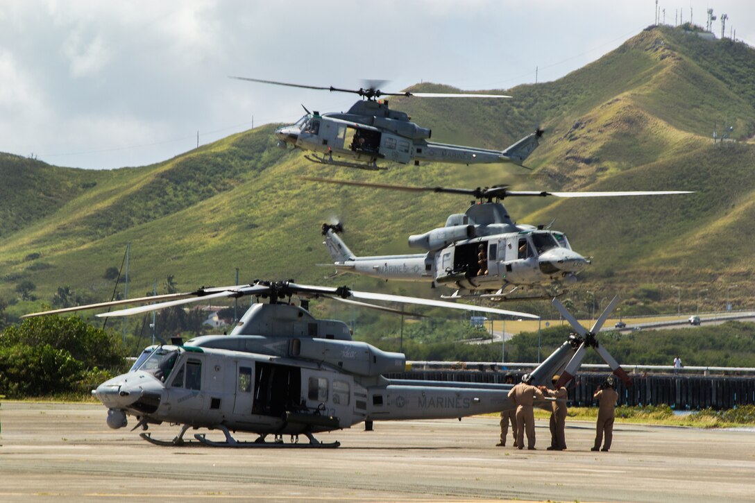 Marines with Marine Light Attack Helicopter Squadron 367 begin prepping a UH-1Y Huey helicopter for takeoff as two others prepare to land aboard Marine Corps Air Station Kaneohe Bay, Hawaii, May 6, 2014. Marine Aircraft Group 24 conducted a max launch of 11 total UH-1Y Huey and AH-1W SuperCobra helicopters assigned to HMLA-367 and CH-53E Super Stallion helicopters assigned to Marine Heavy Helicopter Squadron 463 in an effort to increase unit cohesion and camaraderie within the MAG. While HMLA-367 and HMH-463 conducted operations in the air, Marine Wing Support Detachment 24 and Marine Aviation Logistics Squadron 24 were on the ground to provide forward arming and refueling points, giving MAG-24 a chance to work as a whole. After conducting flight operations, the aircraft returned to MCAS Kaneohe Bay and completed their max launch with a flyby over Marine Corps Base Hawaii before landing. (U.S. Marine Corps photo by Lance Cpl. Matthew Bragg)