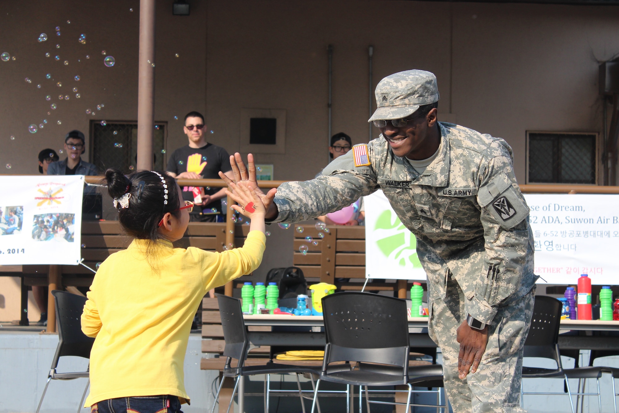 Sgt. Lionel Walker, a medic assigned to Headquarters and Headquarters Battery, 6th Battalion 52nd Air Defense Artillery, gives a “high five” to a child from the House of Dreams orphanage on Suwon Air Base, Republic of Korea, during their visit to the battalion’s headquarters May 6, 2014. The 6-52 ADA is partnered with the orphanage as part of the U.S. Forces Korea Good Neighbor Program. (Photo by KATUSA Pfc. Shin, Young 6-52 ADA)  