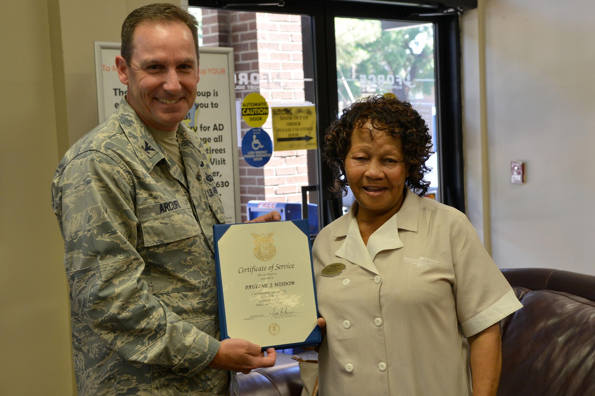 Pauline Wisdom, Carolina Pines Inn housekeeper, receives a 20- year certificate of service from U.S. Air Force Col. Scott Arcuri, 20th Mission Support Group commander, Shaw Air Force Base, S.C., May 7, 2014. Wisdom has been a housekeeper for 26 years, spending her first six years in the business at Pope Air Force Base, N.C. and 20 years at Carolina Pines Inn which is the on base lodging for guest. (U.S. Air Force photo by Senior Airman Ashley L. Gardner/Released)
