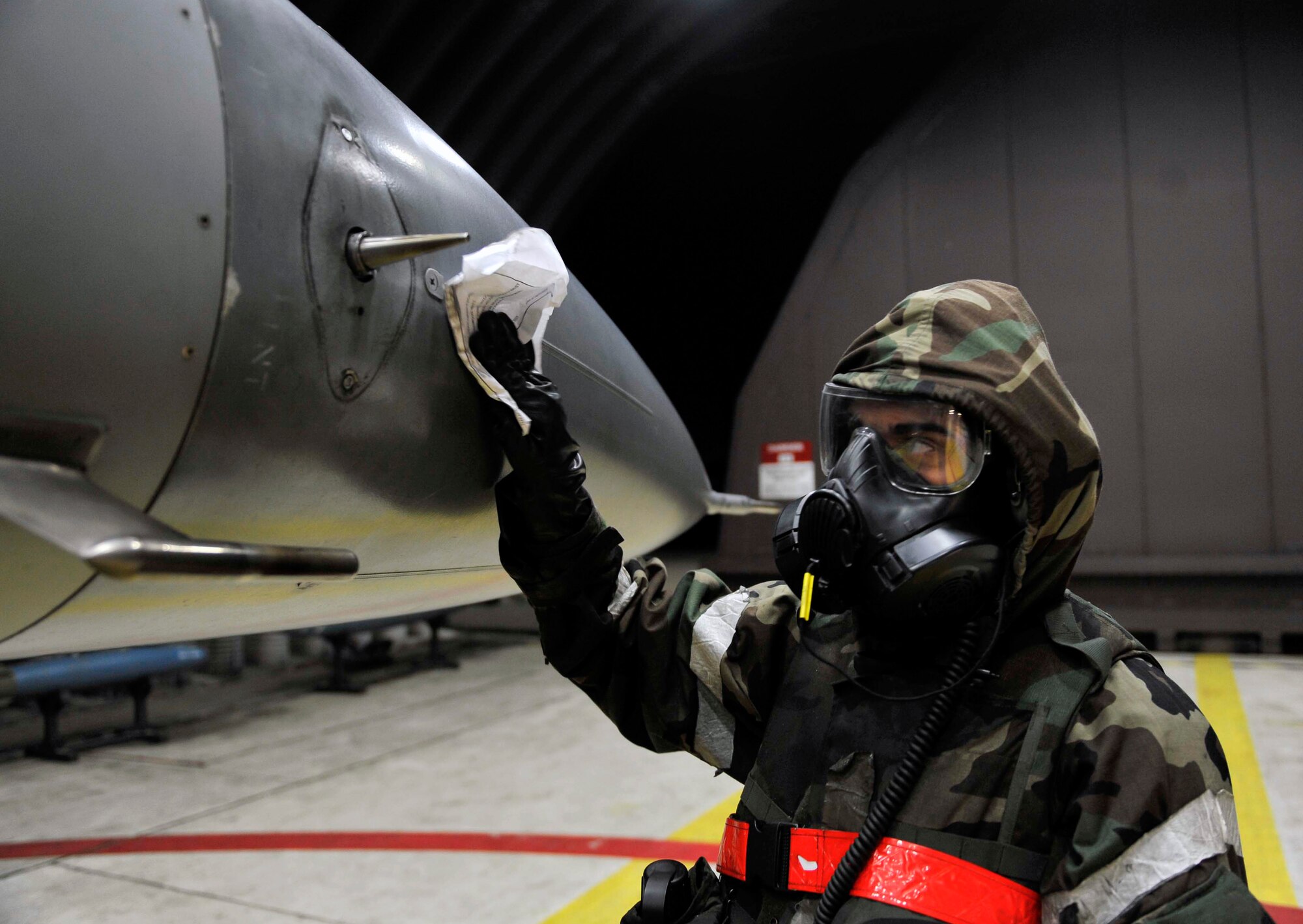 Senior Airman Rafael Martinez, 36th Aircraft Maintenance Unit crew chief, decontaminates the F-16 fighter jet in a hangar after the VX nerve agent were released into the air during a theater ballistic missile attack scenario May 8 on Osan Air Base, Republic of Korea. Decontaminating the aircraft helps ensure the pilot can safely complete his mission. (U.S. Air Force photo by Senior Airman David Owsianka)