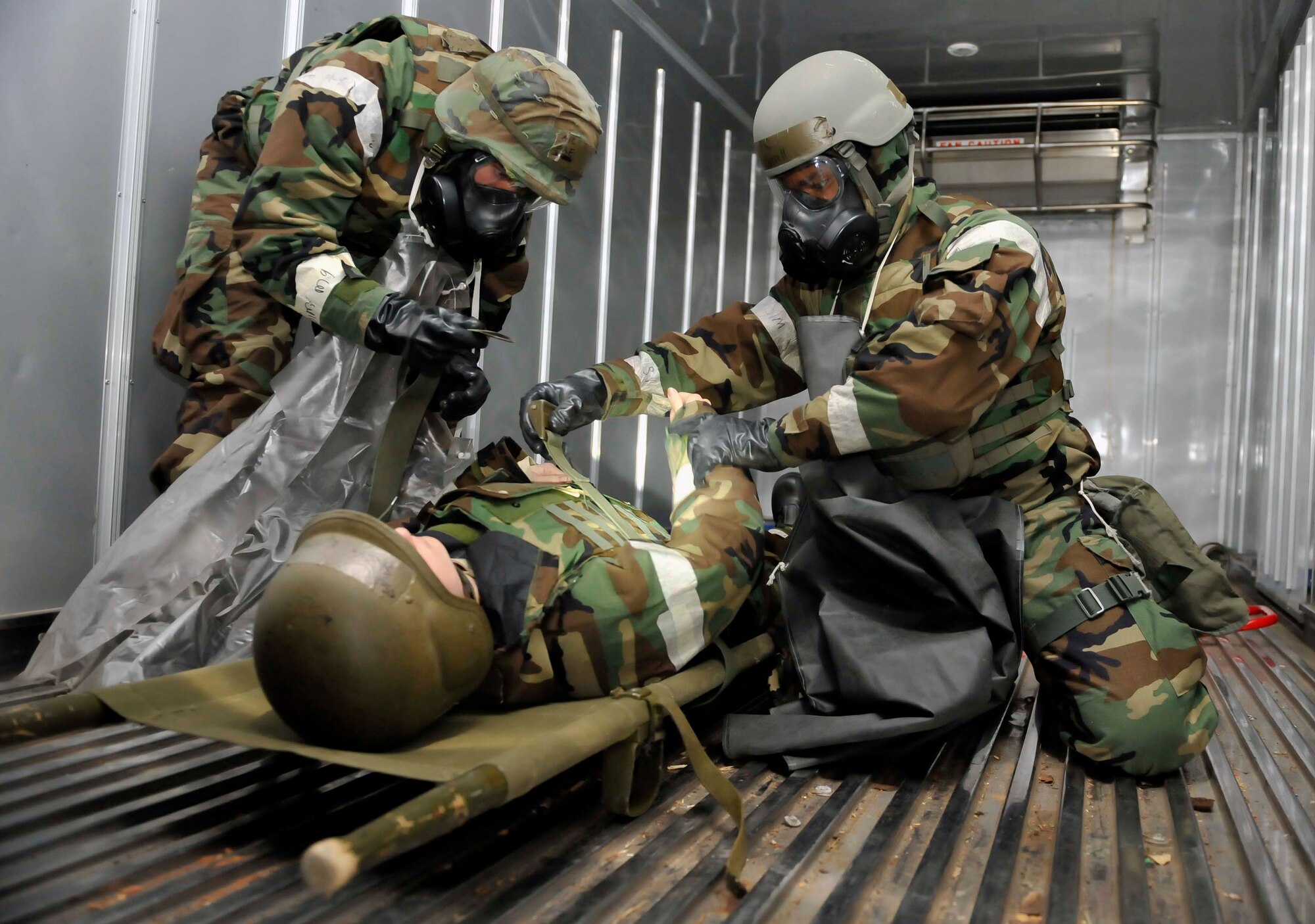 Airmen from Mortuary Affairs tighten the straps on the NATO litter on Staff Sgt. Stashia Murphy, 51st Force Support Squadron, on the golf course after she was a simulated casualty from the theater ballistic missile attack scenario May 8 on Osan Air Base, Republic of Korea. The simulated contaminated casualties would remain on the golf course until hostilities ceased and the casualties could be safely decontaminated. (U.S. Air Force photo by Senior Airman David Owsianka)