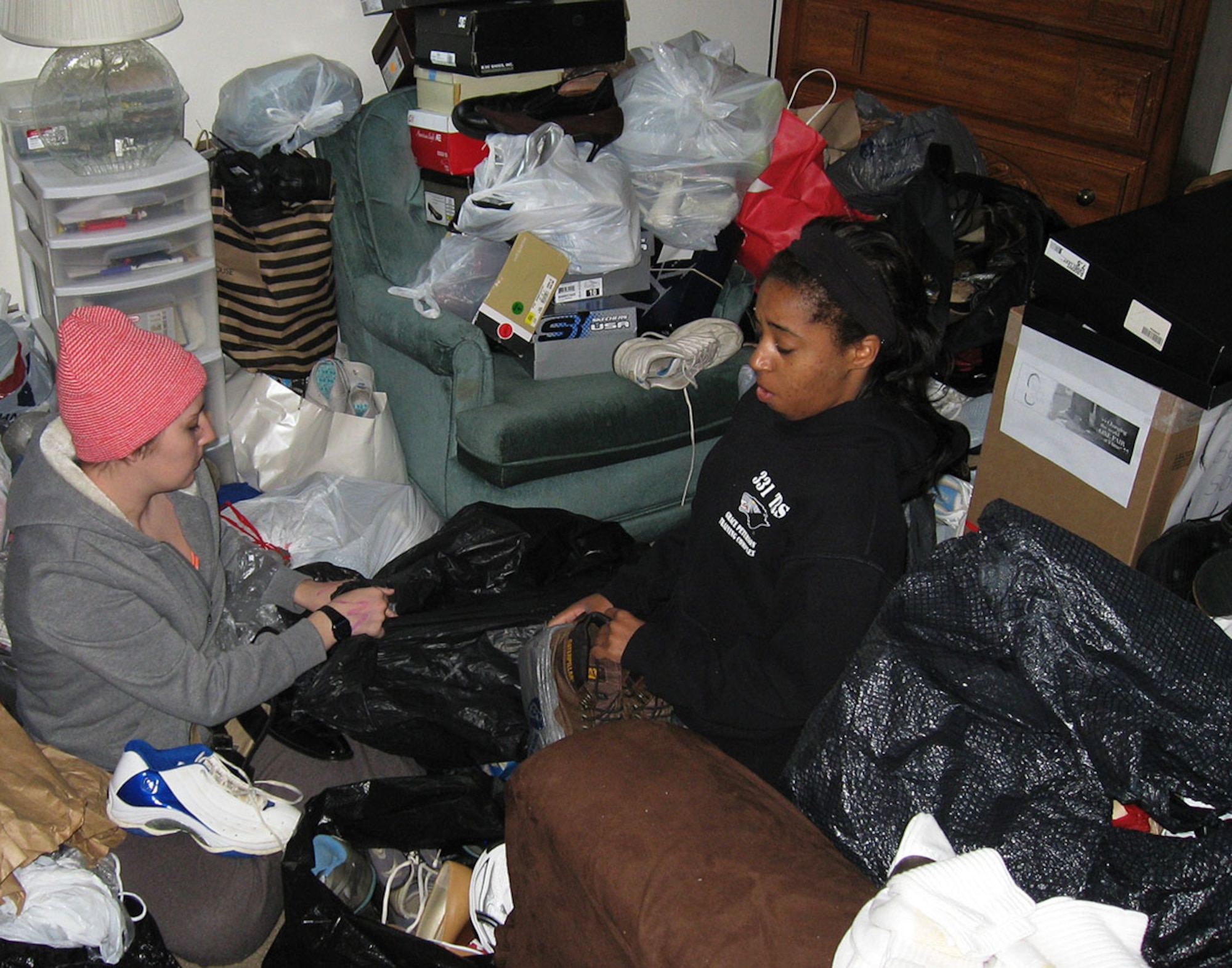 A1Cs Bethany Baines left and Jalynn Wilford both from the 88 Force Support Squadron sit on the bedroom floor surrounded by donated shoes that had to be match and bagged for the Soles4Souls drive. (photo by Ted Theopolos)