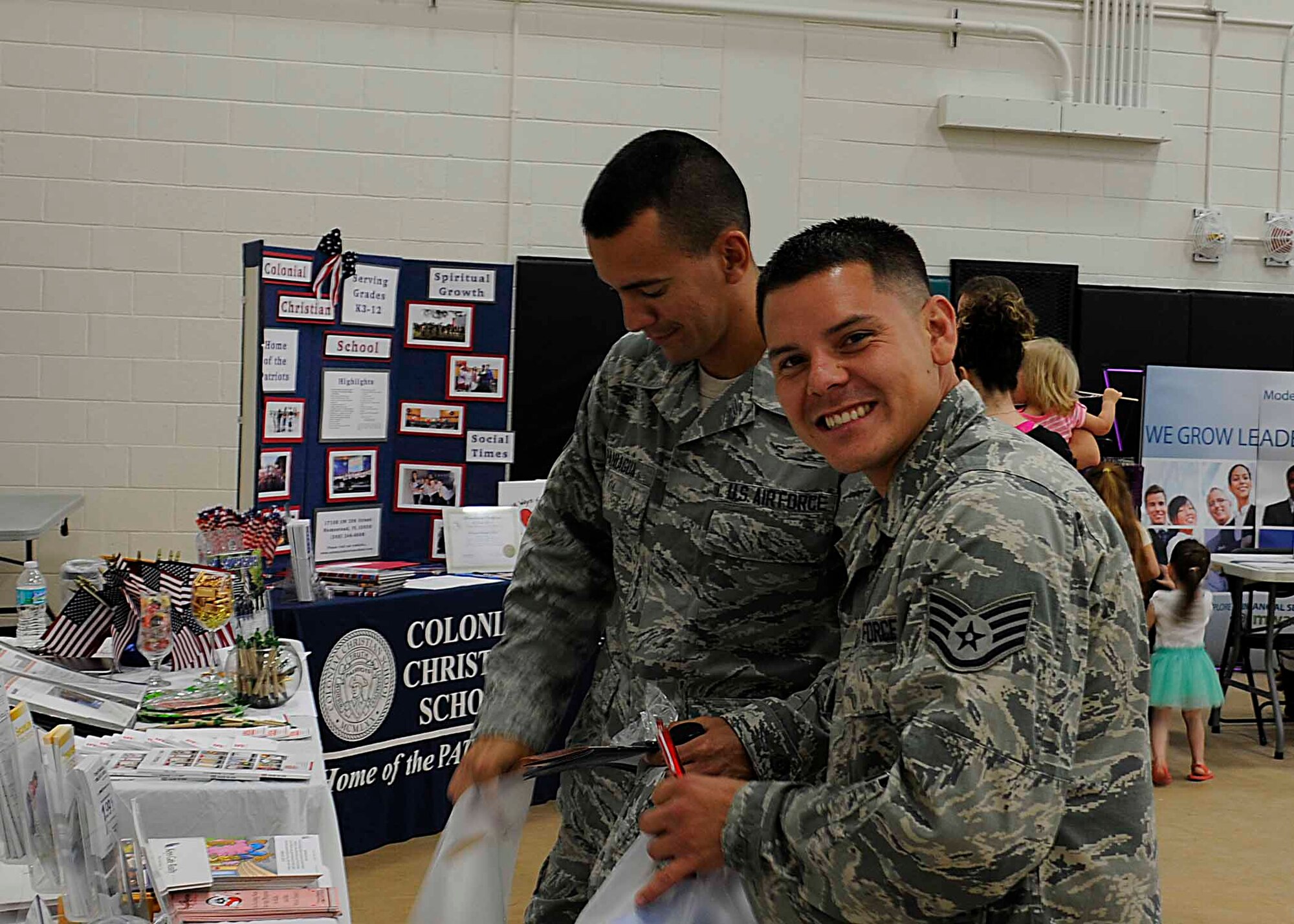Staff Sgt. Isaiah Escorcia, 70th Aerial Port Squadron, and Senior Airman Juan Paniagua, 70th APS, try samples and pick up giveaways from the booths at the first Spring Bazaar in the Sam Johnson Fitness Center at Homestead Air Reserve Base, Fla., on May 3. Escorcia shows his excitement at being able to attend the event. (U.S. Air Force photo by/Senior Airman Aja Heiden)