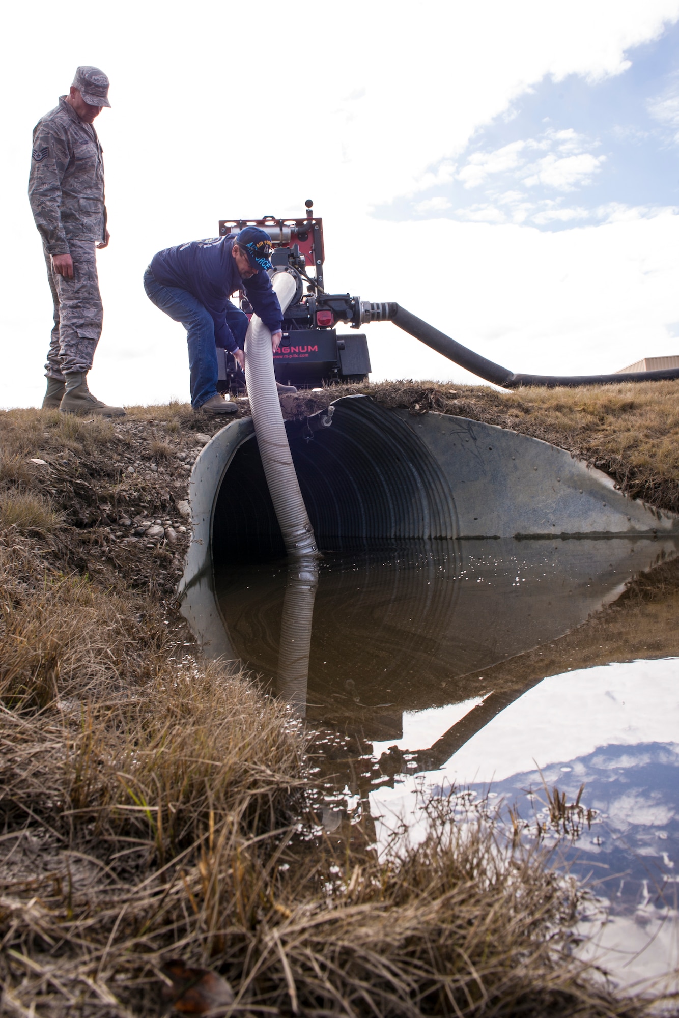 Staff Sgt. Ryan Halter, 354th Civil Engineer Squadron pavements and construction journeyman, and William Ferenc, 354th CES engineering equipment operator supervisor, pump water out of a culvert April 22, 2014, Eielson Air Force Base, Alaska. The Dirt Boyz fixed many areas around base to control flooding and prevent water damage to base facilities. (U.S. Air Force photo by Senior Airman Joshua Turner/Released)