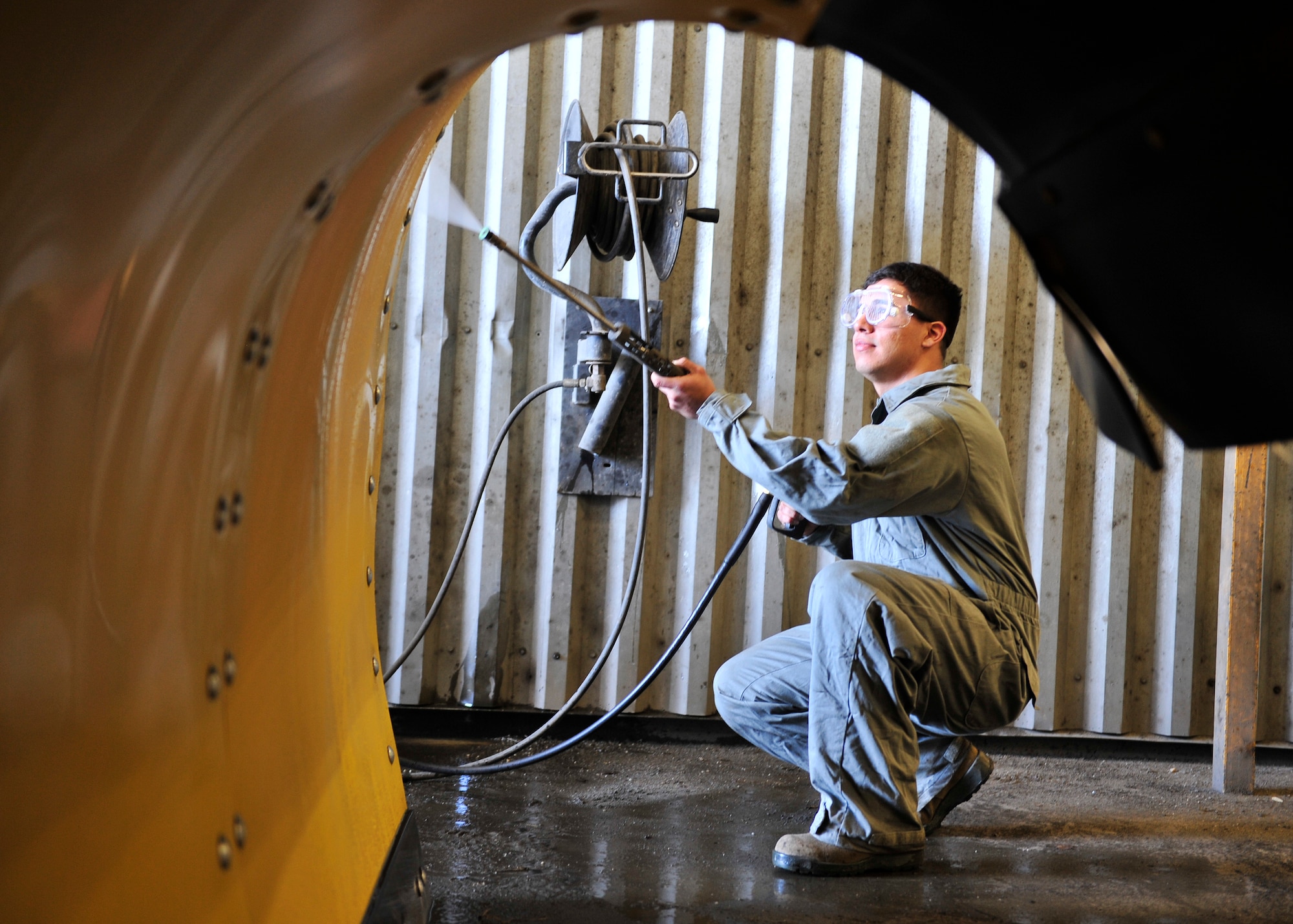 Senior Airman Jorge Robles, 354th Civil Engineer Squadron heavy equipment operator, power washes the front of a snow plow April 28, 2014, Eielson Air Force Base, Alaska. Robles cleaned grime off of the snow plow that accumulated during last winter. (U.S. Air Force photo by Senior Airman Ashley Nicole Taylor/Released)