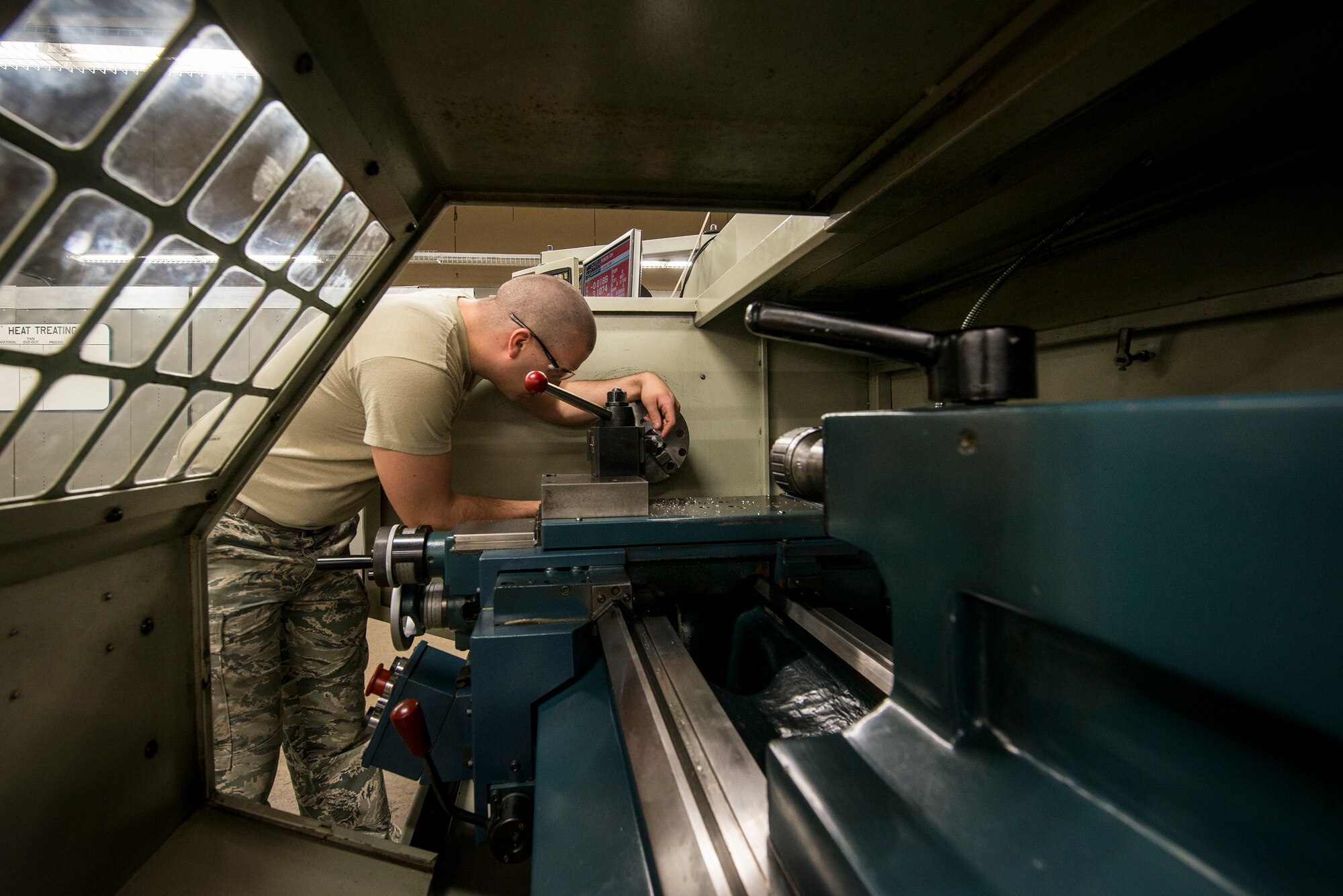 U.S. Air Force Airman 1st Class Cameron Pugh, 23d Equipment Maintenance  aircraft metals technology journeyman, uses a lathe to slowly carve a piece of metal down to the necessary size at Moody Air Force Base, Ga., April 30, 2014. Pugh was making air bleed ducts for an HC-130P Combat King II. (U.S. Air Force photo by Airman 1st Class Ryan Callaghan/Released)