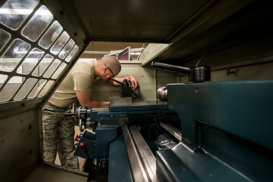 U.S. Air Force Airman 1st Class Cameron Pugh, 23d Equipment Maintenance  aircraft metals technology journeyman, uses a lathe to slowly carve a piece of metal down to the necessary size at Moody Air Force Base, Ga., April 30, 2014. Pugh was making air bleed ducts for an HC-130P Combat King II. (U.S. Air Force photo by Airman 1st Class Ryan Callaghan/Released)