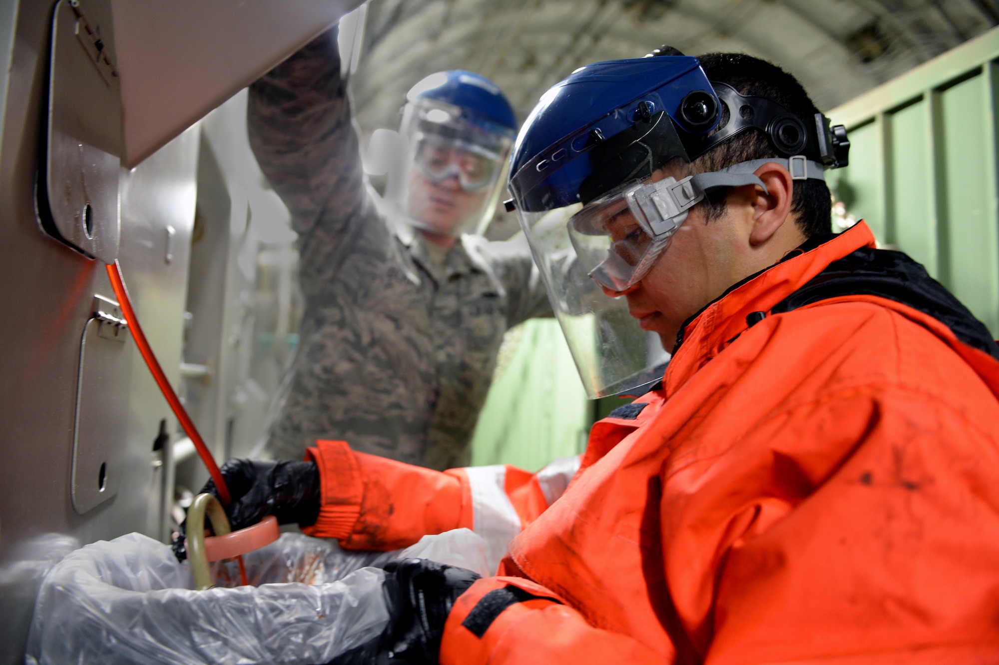 U.S. Air Force Staff Sgt. John Oliver, 726th Air Mobility Squadron hydraulics craftsman from Asheville, N.C., and U.S. Air Force Senior Airman Nestor Fraga, 726th Air Mobility Squadron crew chief from Crossville, Tenn., drain hydraulic fluid from a U.S. Air Force C-17 Globemaster III Cargo Aircraft system at Spangdahlem Air Base, Germany, May 7, 2014. AMS Airmen conducted checks and servicing on the C-17 as part of a post-flight inspection. (U.S. Air Force photo by Senior Airman Alexis Siekert/Released)