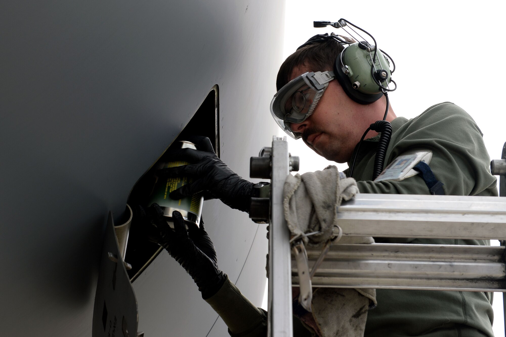 U.S. Air Force Staff Sgt. Paul Coblentz, 726th Air Mobility Squadron crew chief from Milwaukee, performs engine oil servicing on a U.S. Air Force C-17 Globemaster III Cargo Aircraft at Spangdahlem Air Base, Germany, May 7, 2014. The AMS team recovered the C-17 before it continued to Afghanistan. (U.S. Air Force photo by Senior Airman Alexis Siekert/Released)