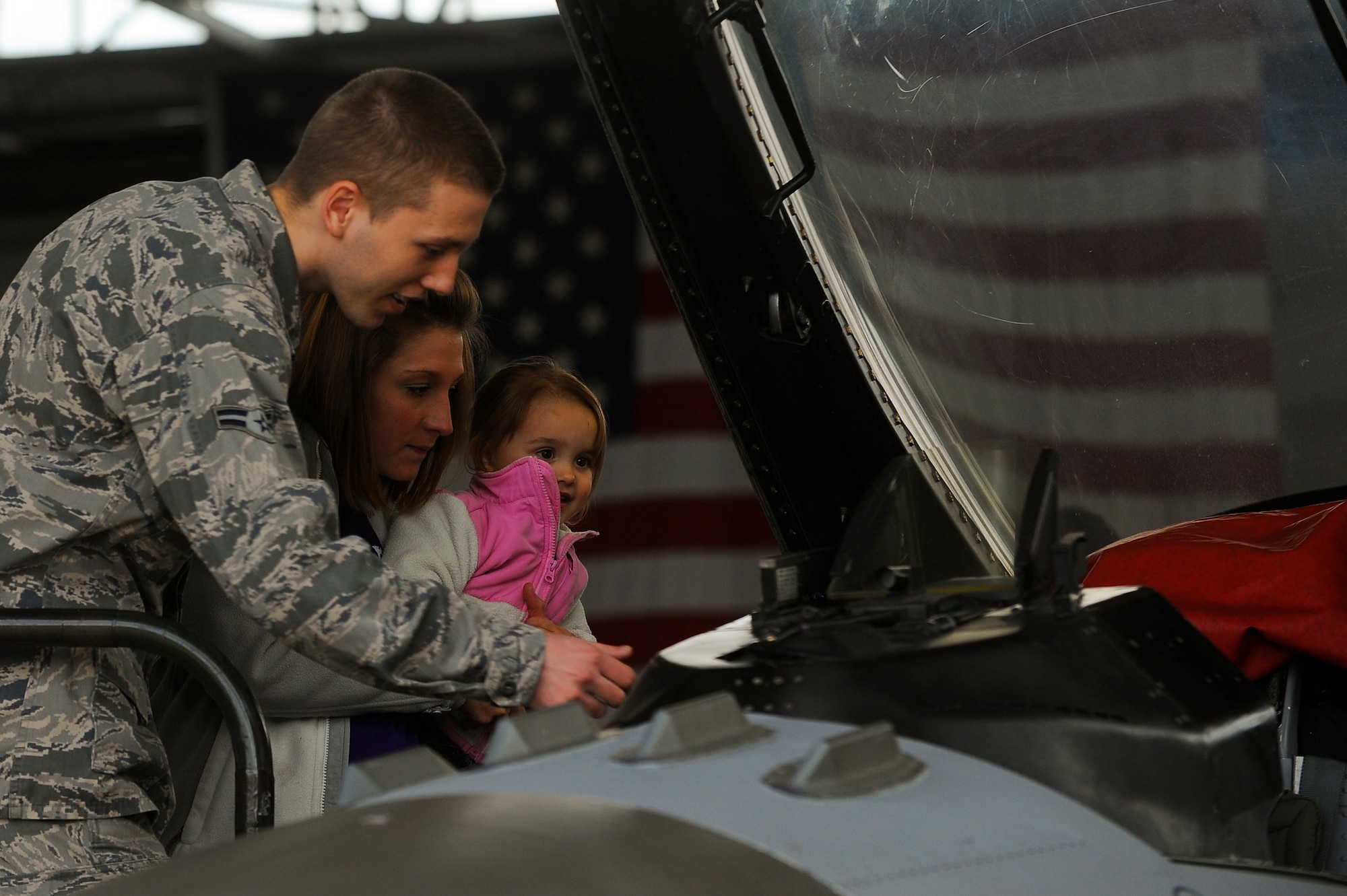 Nicole Tart, spouse of U.S. Air Force 2nd Lt. Lewis Tart, 52nd Maintenance Group assistant officer in charge of maintenance operations, and their daughter McKenley Tart, 2, look at the cockpit of a U.S. Air Force F-16 Fighting Falcon fighter aircraft during a 52nd MXG spouses tour May 8, 2014, at Spangdahlem Air Base, Germany. Spouses toured 52nd MXG facilities to learn how their loved ones contribute to the wing mission. (U.S. Air Force photo by Senior Airman Rusty Frank/Released)