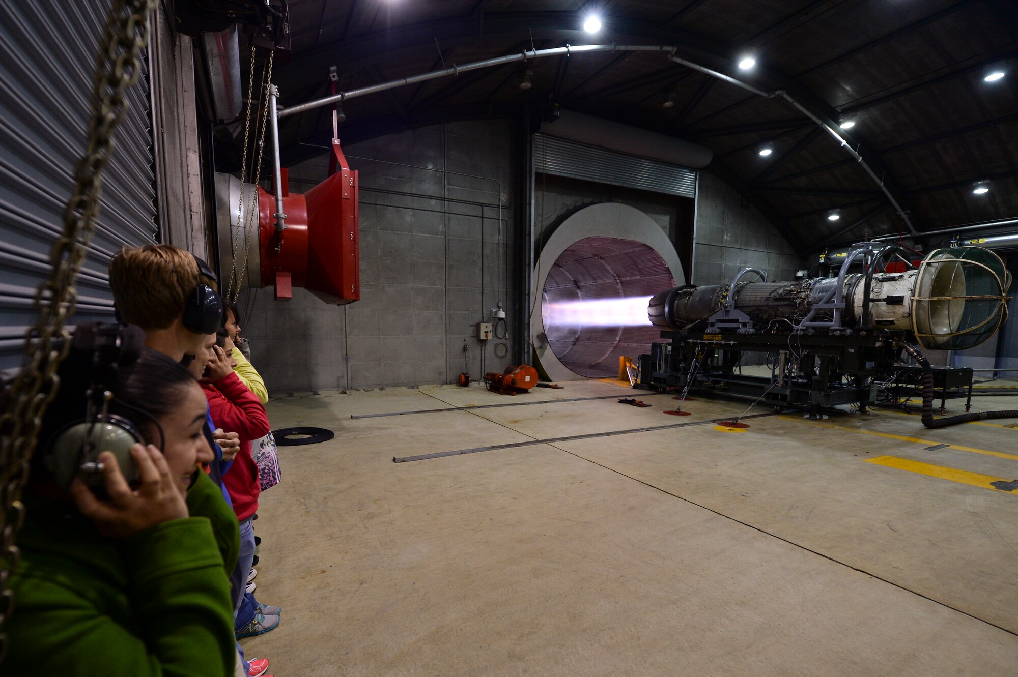 Military spouses watch a U.S. Air Force F-16 Fighting Falcon fighter aircraft engine run inside the “Hush House” during a 52nd Maintenance Group spouses tour May 7, 2014, at Spangdahlem Air Base, Germany. As a part of the tour that was held to celebrate Military Spouse Appreciation Day, the spouses toured many facilities including the “Hush House,” sheet metal and fuel barn. (U.S. Air Force photo by Senior Airman Rusty Frank/Released)