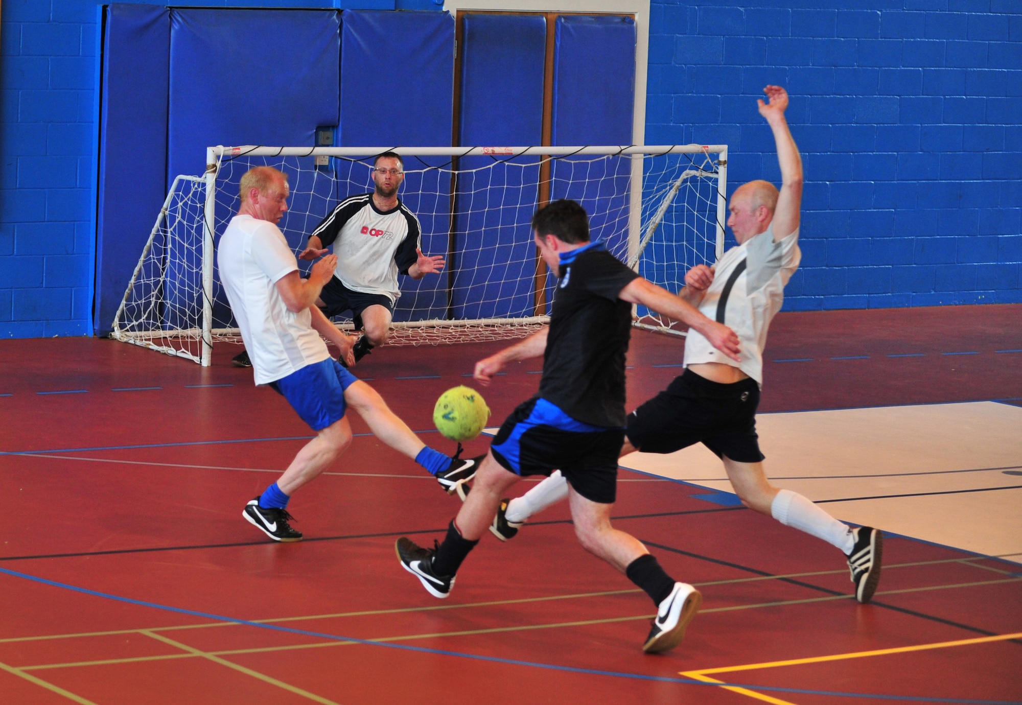 Members of the 100th Civil Engineer Squadron and the 100th Force Support Squadron indoor soccer teams battle for dominance May 6, 2014, during an indoor soccer championship on RAF Mildenhall, England. The 100th CES team won 8-6. (U.S. Air Force photo by Staff Sgt. Krystie Martinez/Released)