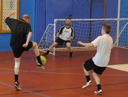 Gary Butcher, left, 100th Force Support Squadron accounting technician from Cambridge, England, attempts a goal as Barry King, center, 100th Civil Engineer Squadron storekeeper from Lakenheath, England, moves to defend during an indoor soccer championship May 6, 2014, at RAF Mildenhall, England. The 100th CES team won 8-6 to take home the trophy. (U.S. Air Force photo by Tech. Sgt. Neal X. Joiner/Released)