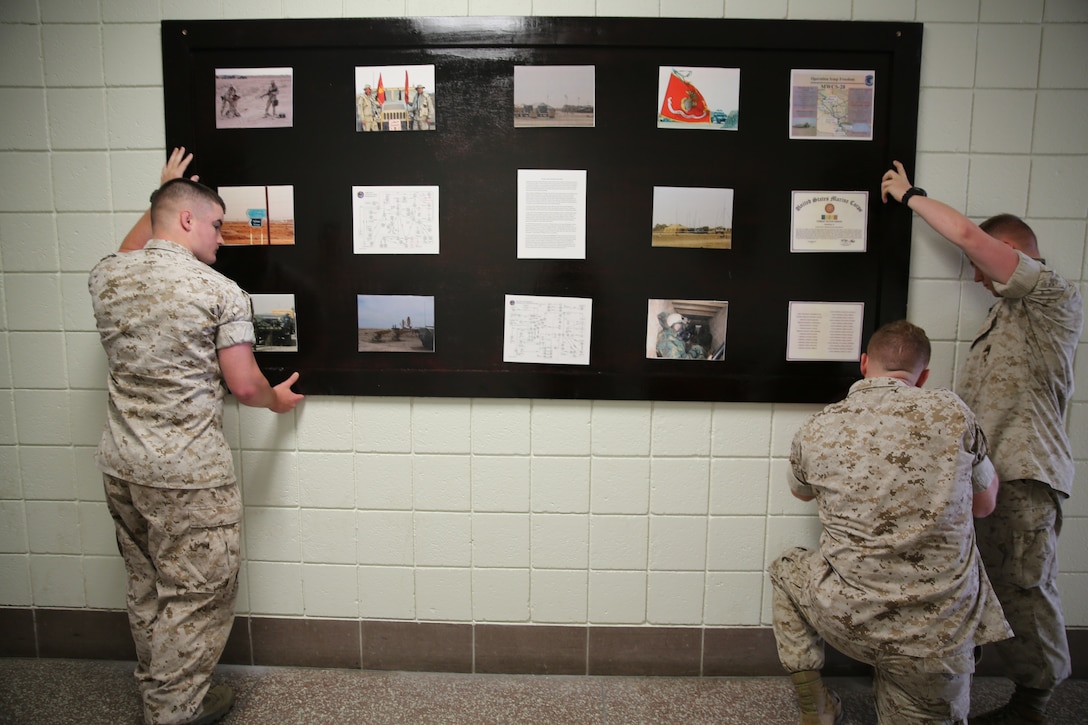 Marines with Marine Wing Communications Squadron 28 hang a display board of the squadron’s latest accomplishments here, May 1. The display board is an addition to the squadron’s Hall of History, created by Marines within the squadron as a reminder of the Marine’s history and accomplishments. The creation of the Hall of History is one of the steps the squadron is taking to help them get back to the basics. 