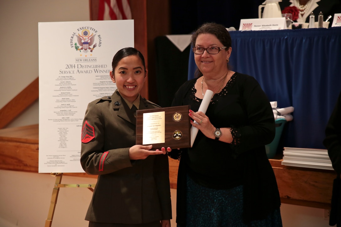 Sergeant Ger Maginnis, a supply administration and operations specialist with 4th Marine Aircraft Wing, Marine Forces Reserve, receives a Distinguished Service Award as the Outstanding Military Noncommissioned Officer from Trinia Bax, the chairwoman of the 2014 Public Service Recognition Week Committee at the University of New Orleans, May 7, 2014. The board coordinates an award presentation to recognize the dedication and hard work of federal, state and local government employees each year in May. The Distinguished Service Award is presented to the most outstanding employees in 16 award categories. Three Marines and two civilian employees within Marine Forces Reserve received the Distinguished Service Award. (U.S. Marine Corps photo by Cpl. Codey Underwood)