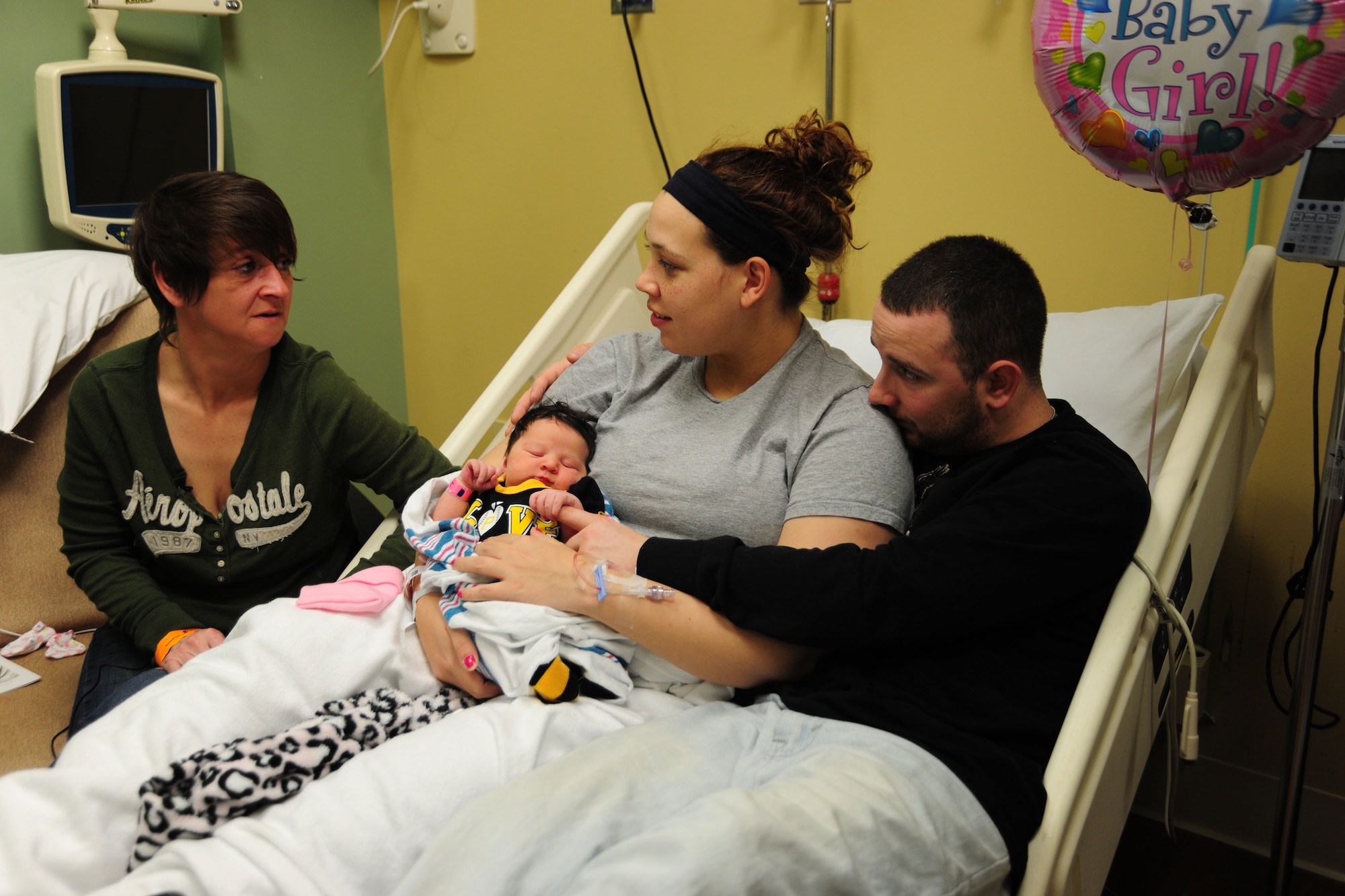 Airman 1st Class Samuel DeWitt (right), and his wife Kaila look to Kaila’s mother, Ginger Preston, for parental guidance and support as they share a moment with their newborn daughter Kynnedie at MedStar Southern Maryland Hospital on March 31,2014. DeWitt, 79th Medical Staging Squadron diet therapy apprentice, and Kaila said Preston is their hero. (U.S. Air Force photo / Amber J. Russell)