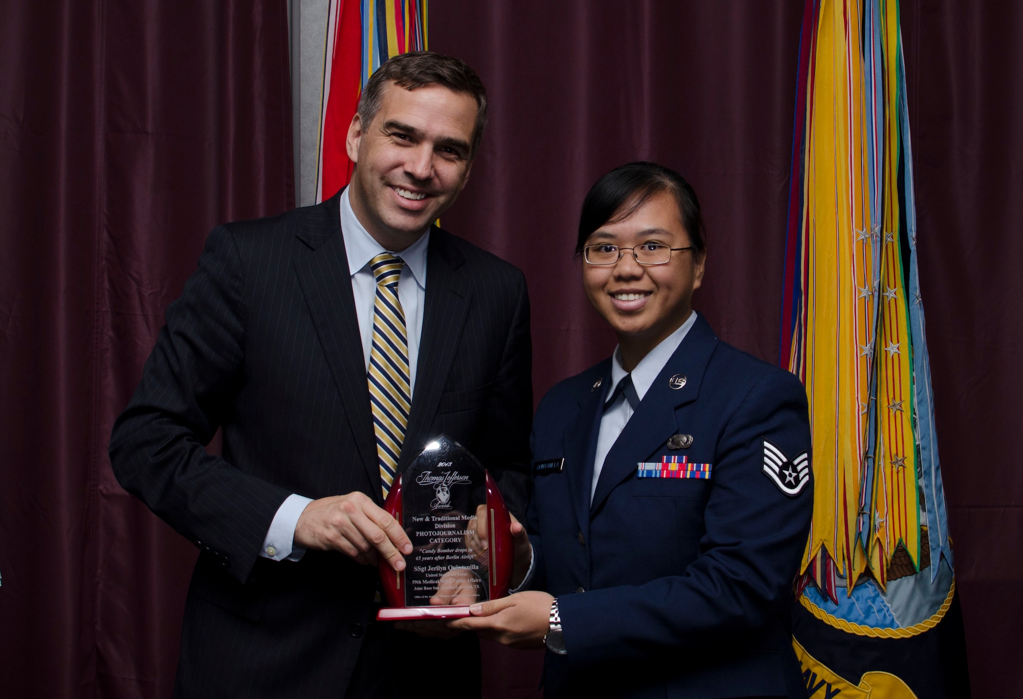 Staff Sgt. Jerilyn Quintanilla, 59th Medical Wing Public Affairs at JBSA-Lackland, Texas, receives the Thomas Jefferson Award (photojournalism category) from Brent Colburn, Assistant to the Secretary of Defense for Public Affairs, during an award ceremony at the Defense Information School, Fort George G. Meade, Maryland May 9, 2014. Quintanilla won for her combined skills in writing and photography, which she used to tell the story about the “Candy Bomber” and his reenactment of delivering candy to children during the Berlin Airlift campaign. (Courtesy photo) 
