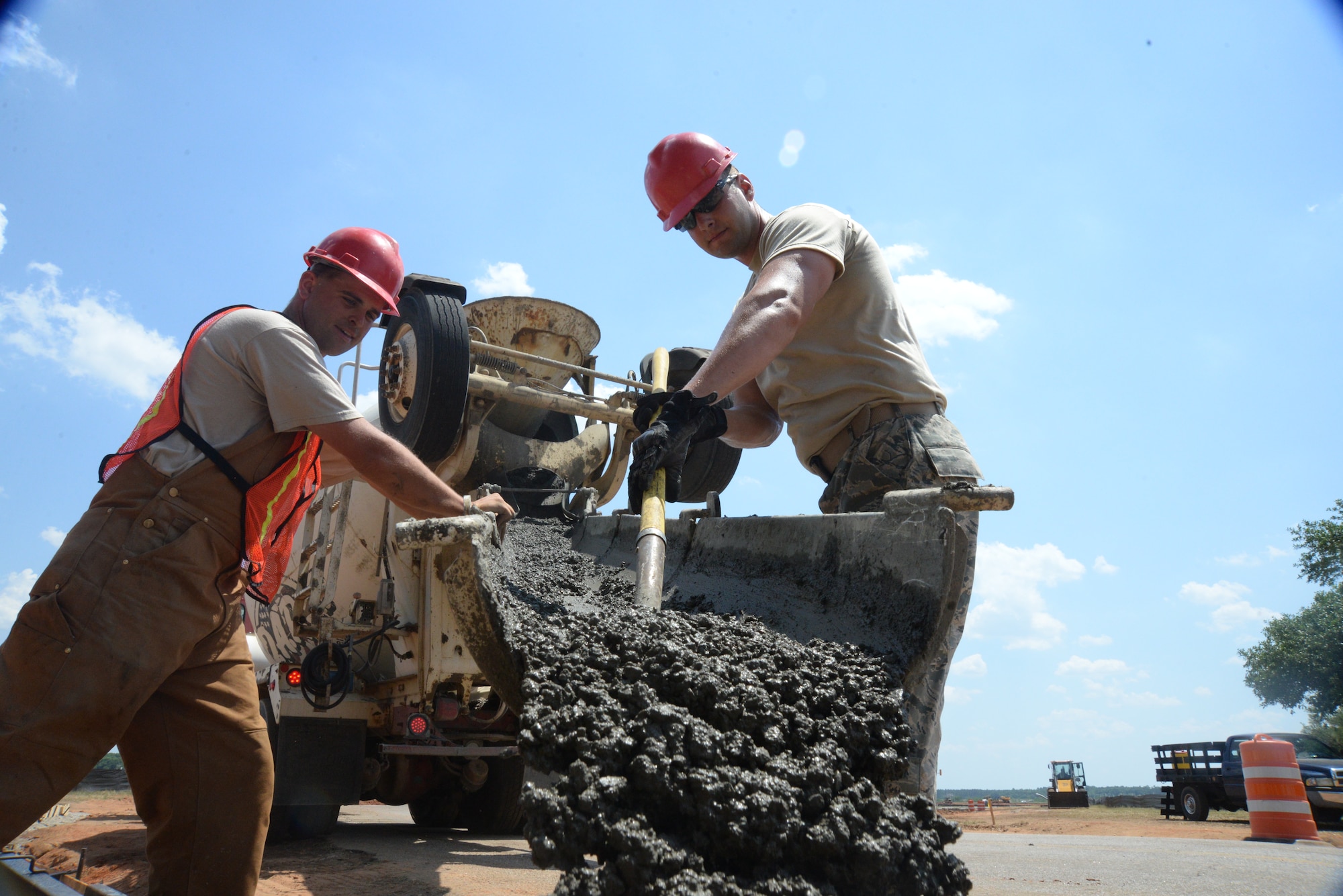 [Left to right] U.S. Air Force Staff Sgts. Joseph Chalkley and Corey Griffin, 823rd Rapid Engineer Deployable Heavy Operational Repair Squadron Engineers heavy equipment operators assigned to Hurlburt Field, Fla., guide the flow of cement from a cement truck at Shaw Air Force Base, S.C., May 8, 2014. The Airmen work 12 hour shifts, Monday through Saturday to complete the project on time. The primary mission of 823d RED HORSE Squadron is to assess, plan and establish contingency facilities to support contingency operations and combat missions. (U.S. Air Force photo by Airman 1st Class Michael A. Cossaboom/Released)