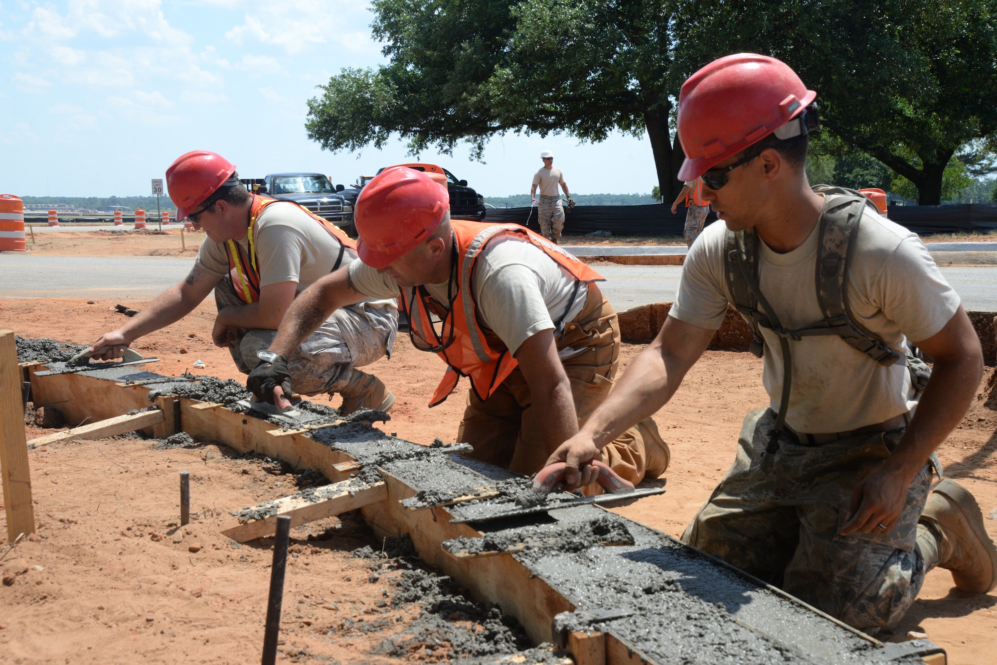 [Left to right] U.S. Air Force Staff Sgt. Jeremiah Holt, Senior Airman Josh Lemanski, and Staff Sgt. Francisco Bautista, 823rd Rapid Engineer Deployable Heavy Operational Repair Squadron Engineers heavy equipment operators assigned to Hurlburt Field, Fla., pave wet cement that will be a new curb along Patrol Road at Shaw Air Force Base, S.C., May 8, 2014.  The RED HORSE Airmen will complete three construction projects while at Shaw AFB that are estimated to cost approximately $4.5 million. (U.S. Air Force photo by Airman 1st Class Michael A. Cossaboom/Released)