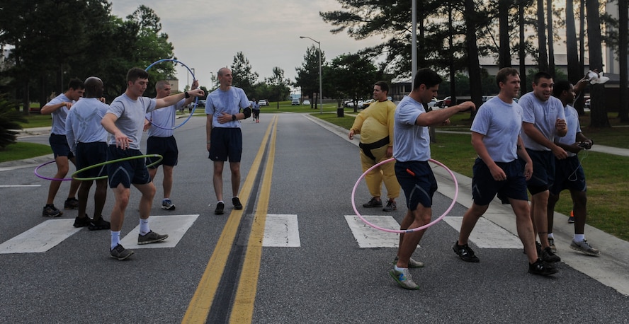 Airmen hula-hoop during a 5k at Moody Air Force Base, Ga., May 9, 2014. In order to finish the run, there was a rice eating station set up and a hula-hoop station Airmen had to complete before crossing the finish line. (U.S. Air Force photo by Airman 1st Class Alexis Millican/Released)