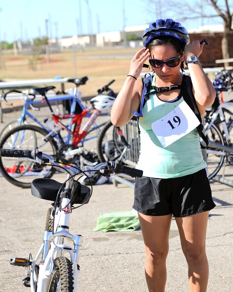 Patricia Rodriguez puts on her helmet for the cycling heat of the Dyess Triathlon May 3, 2014, at Dyess Air Force Base, Texas. Rodriguez swam 425 meters, rode 12.3 miles and ran 3.4 miles in 1 hour, 59 minutes and 56 seconds. She was awarded a $100 gift card for winning the female segment of the triathlon. (U.S. Air Force photo by Airman 1st Class Kedesha Pennant/Released)