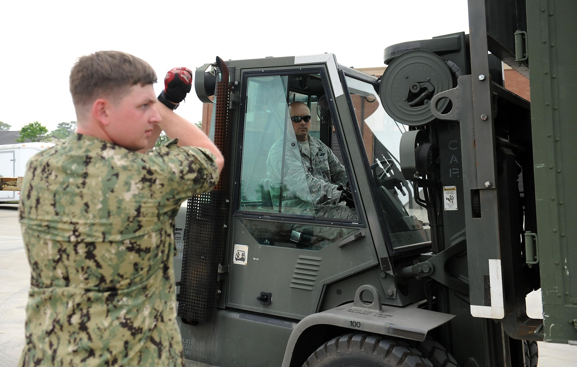 U.S. Air Force Master Sgt. John Allen, loadmaster, Joint Task Force Civil Support, operates a forklift while receiving ground guide signals from U.S. Navy Petty Officer 2nd Class Duane Laughlin, damage controlman, JTF-CS, during an Early Entry Command Post deployment exercise at Fort Eustis, Va., May 8, 2014. JTF-CS is preparing for Sudden Response 2014 which will test the unit's movement of equipment and personnel during the initial phases of a simulated man-made or natural disaster. JTF-CS anticipates, plans and prepares for chemical, biological, radiological and nuclear defense support to civil authorities response operations. (Official DOD photo by U.S. Navy Petty Officer 1st Class Brian Dietrick))