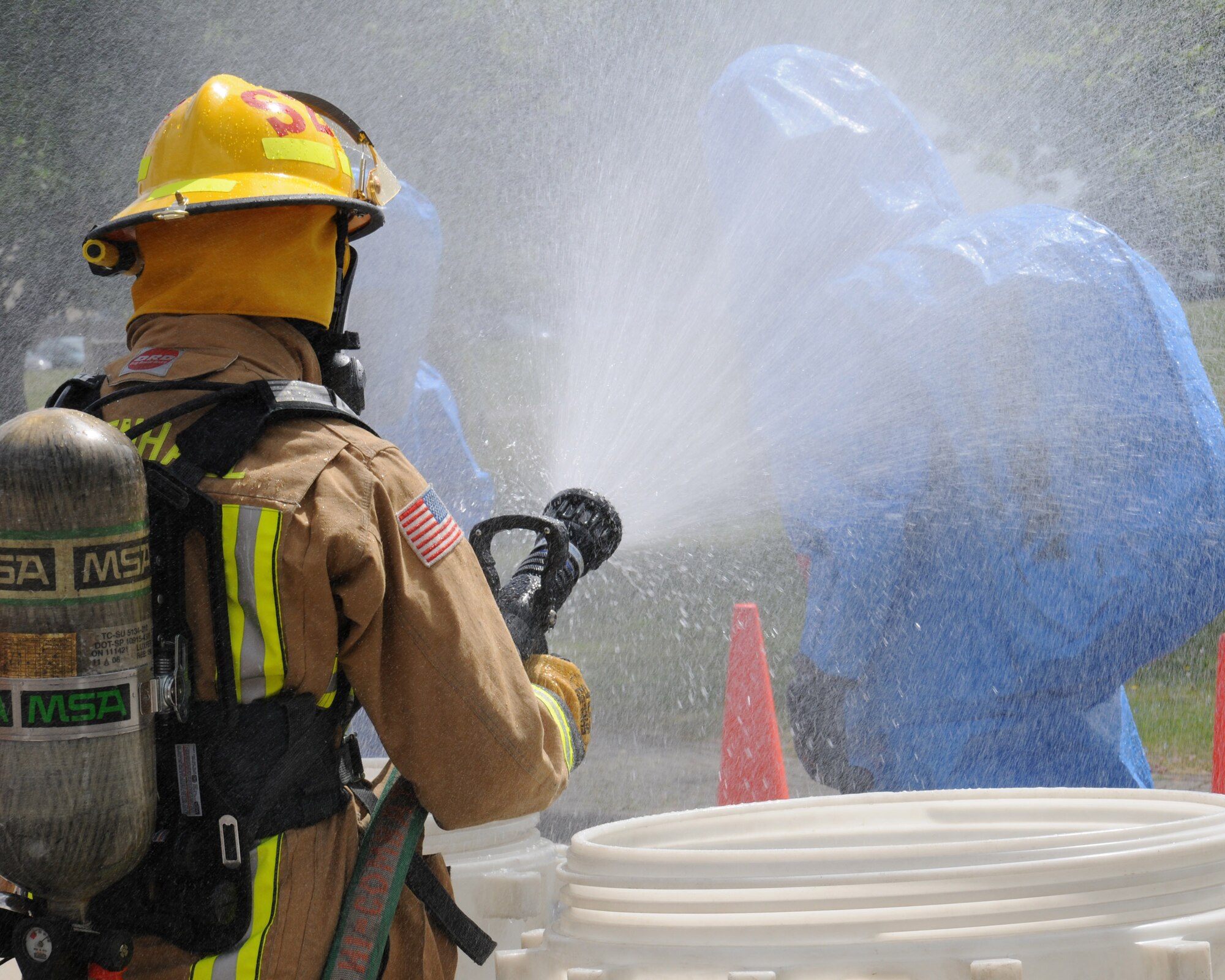U.S. Air Force Airman 1st Class Jacob Sandoval, 100th Civil Engineer Squadron Fire Department firefighter from San Antonio, uses a hand line to clean potentially hazardous chemicals from another firefighter’s clothing during a hazardous materials exercise May 6, 2014, on RAF Mildenhall, England. The hand line is known as a decontamination line. (U.S. Air Force photo by Gina Randall/Released)