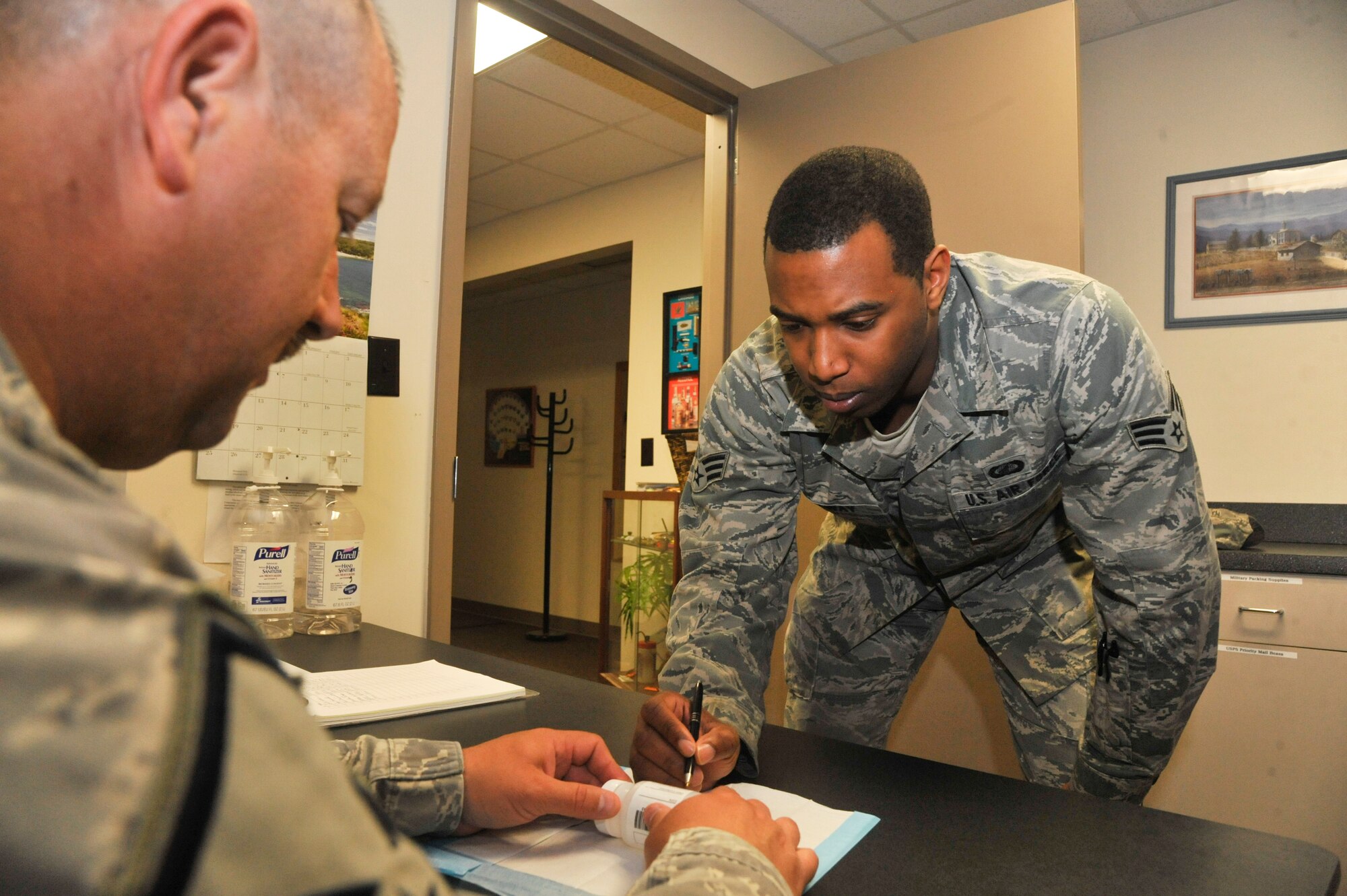 U.S. Air Force Senior Airman Bryon Caraway, 509th Comptroller Squadron finance specialists, initials a specimen bottle while Master Sgt. Todd Schafer, 509th Bomb Wing drug testing program administrative manager, observes at Whiteman Air Force Base, Mo., May 8, 2014. This procedure is done to confirm the sample belongs to the member. (U.S. Air Force photo by Airman 1st Class Keenan Berry/Released)