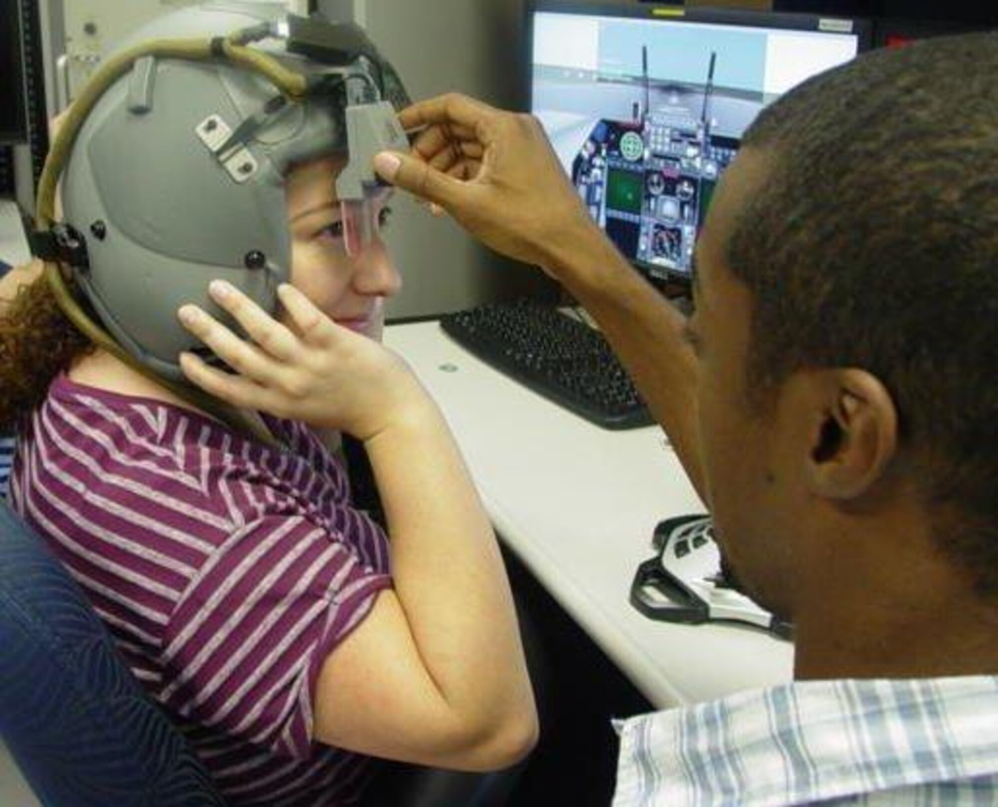 Rickey King, 579th Software Maintenance Squadron computer scientist, adjusts the heads up display on ALQ-213 3-D audio organic software worn by Suzy Crespo, electronics engineer. (U.S. Air Force photo by Ed Aspera)