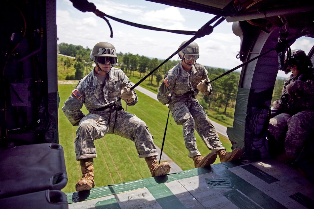 Army Cadets Timothy Dudley, left, and Nicholas Calderon get into position to rappel out of a UH-60 Black Hawk helicopter during the last phase of an air assault course on Fort Benning, Ga., July 23, 2013.  
