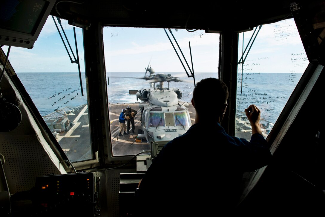 U.S. Navy Ensign Robert Martinez tracks an SH-60S Seahawk helicopter from Helicopter Sea Combat Squadron 12 as it prepares to take off from the flight deck of the guided-missile destroyer USS Preble in the Coral Sea, July 22, 2013. The Preble is participating in Talisman Saber 2013, a biennial training event to improve Australian and U.S. combat readiness and interoperability as a combined task force.  
