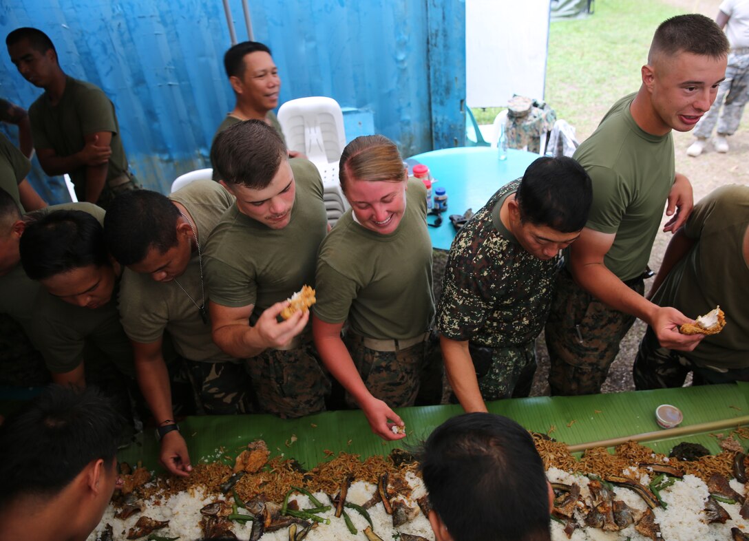 Members of the Armed Forces of the Philippines and U.S. Marines participate in a “boodle fight” at Malobago Elementary School April 29 in Guinobatan, Albay Province, Philippines. During the boodle fight, a traditional Filipino meal, those participating circle around the large pile food that has been dumped on top of banana leaves and grab as much food as possible using only their right hands. Malobago is one of the engineering civic action project sites being renovated as part of Exercise Balikatan, an annual bilateral training exercise and humanitarian assistance engagement between members of the AFP and U.S. armed forces. The Marines are with 9th Engineer Support Battalion, 3rd Marine Logistic Group, III Marine Expeditionary Force. (Photo by U.S. Marine Cpl. Kevin Crist)


