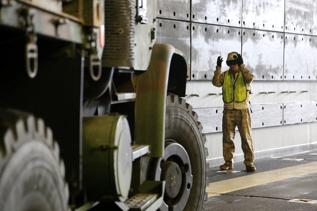 A Marine with Combat Cargo, USS San Diego, ground guides a 7-ton truck in position onto a landing craft air cushion in the well deck of the USS San Diego during Composite Training Unit Exercise off the coast of San Diego, May 8, 2014. COMPTUEX is the second at-sea period during the 11th Marine Expeditionary Unit's predeployment cycle, in which the MEU will conduct concurrent mission planning and execution integrated across all element of the Marine Air Ground Task Force while supporting Amphibious 5 in their evaluated training. (U.S. Marine Corps photo by Gunnery Sgt. Rome M. Lazarus/Released)